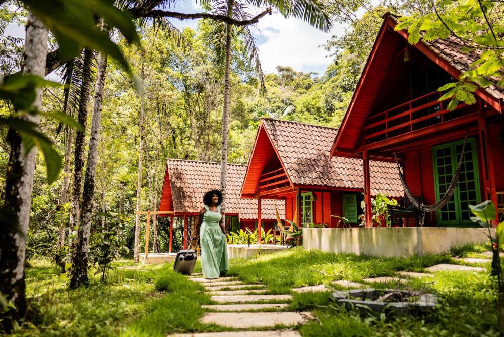 A woman walking through a resort surrounded by lush greenery and wooden houses