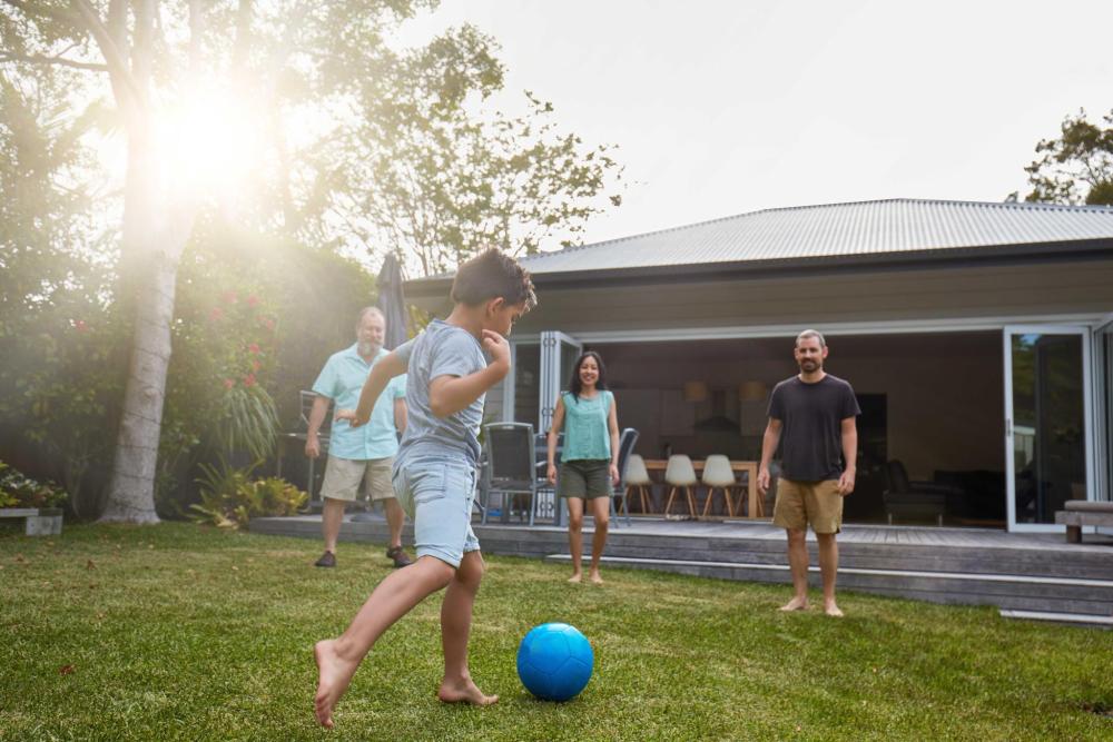 Boy is about to kick the football in front of a modern house