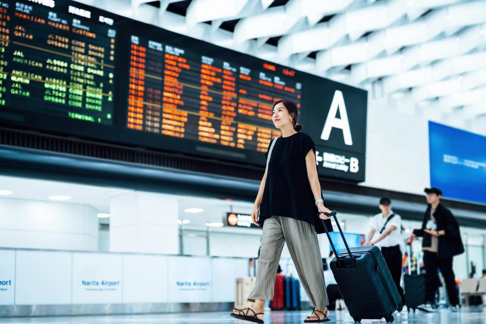 スーツケースを持ち空港を歩く旅行者