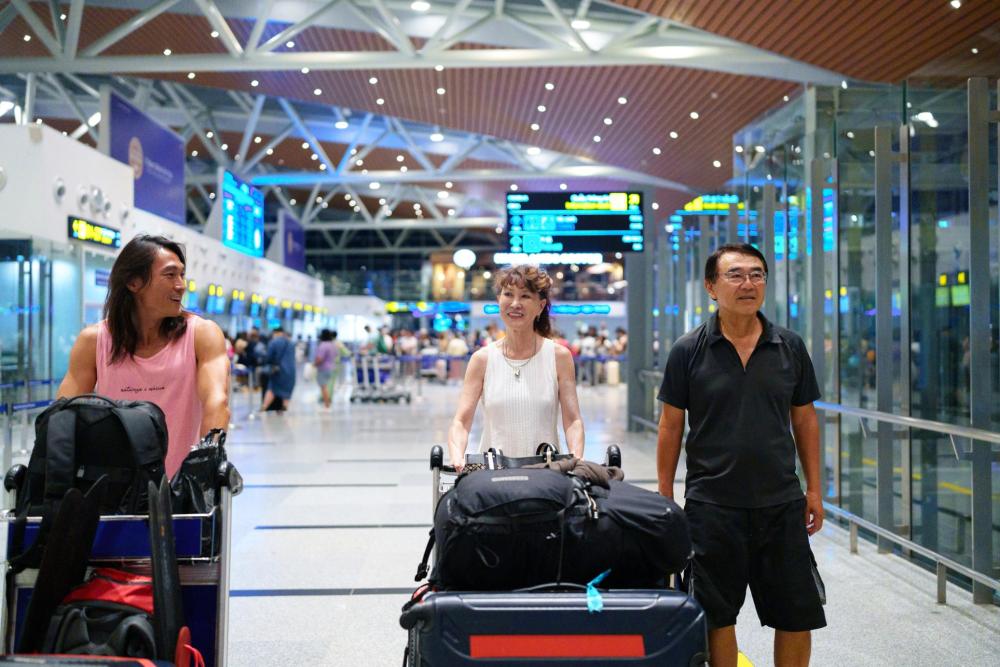 空港で荷物をカートに乗せて運ぶ旅行者