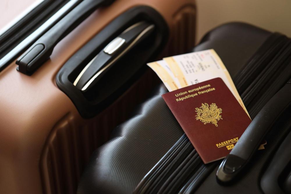 Un passeport français et des cartes d’embarquement posés sur une valise