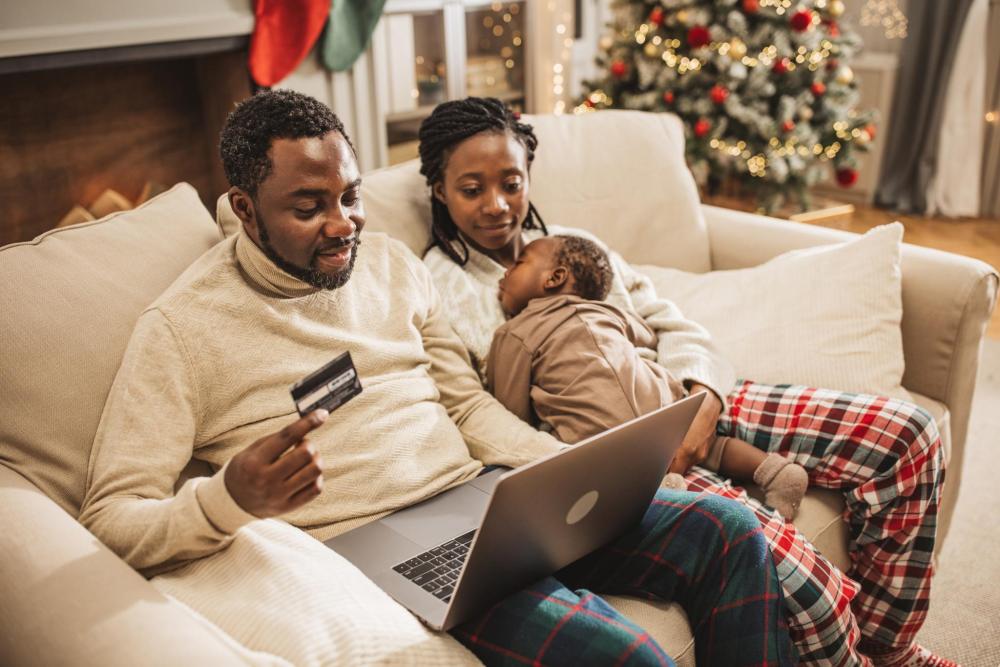 Une famille utilise une carte de crédit pour faire des achats de Noël, entourée de décorations festives