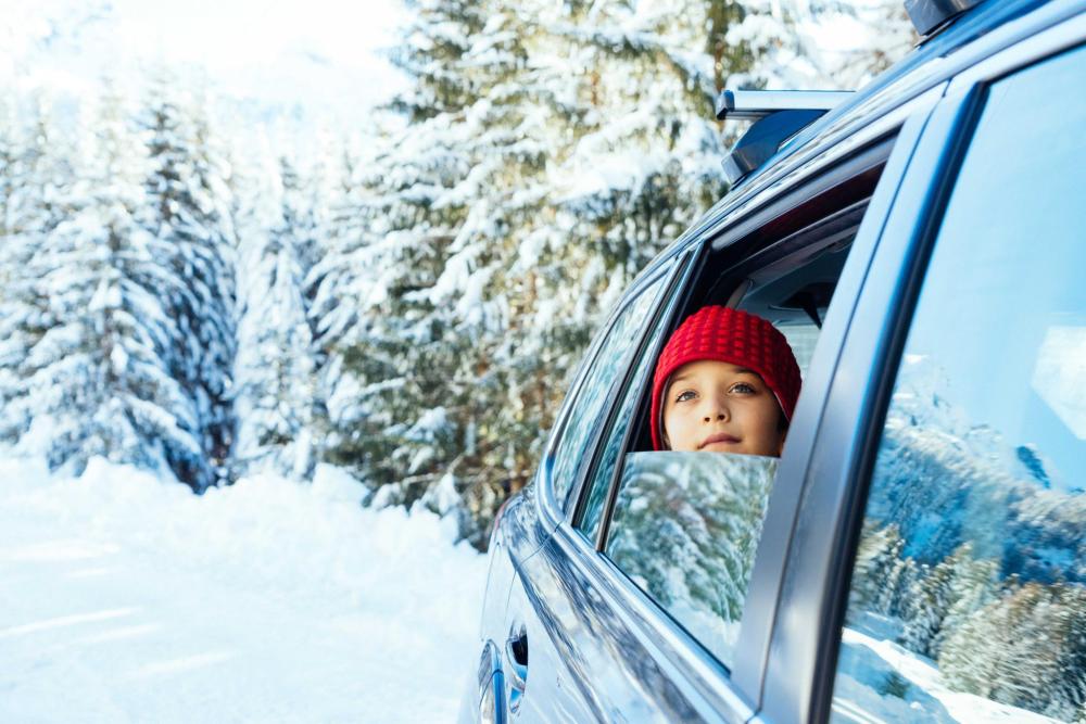 Un enfant regarde par la fenêtre d'une voiture, observant un paysage enneigé