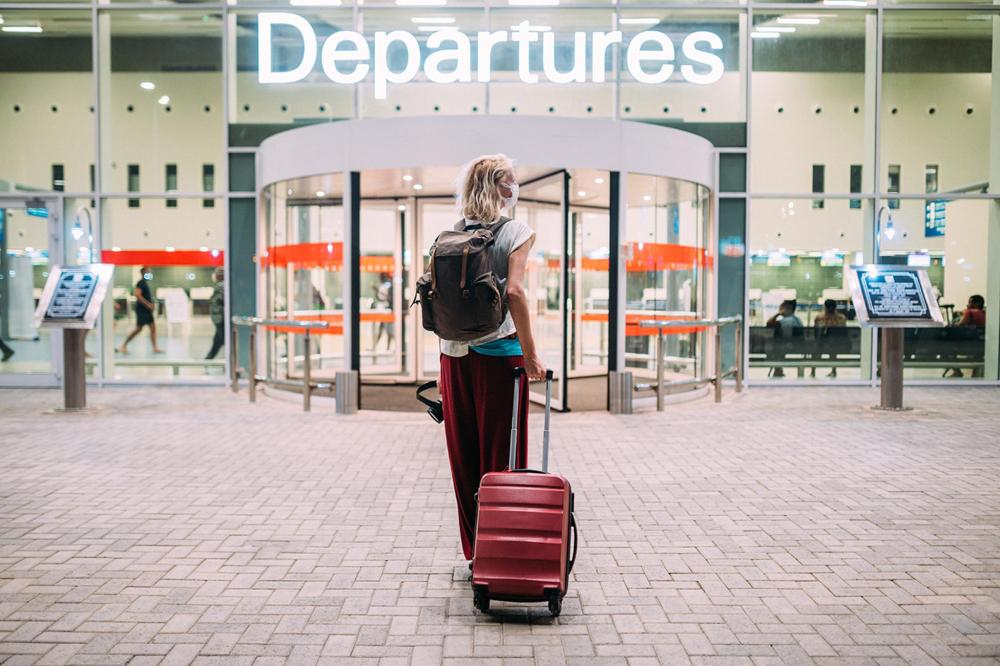 Femme marchant une valise à la main vers un terminal d'aéroport