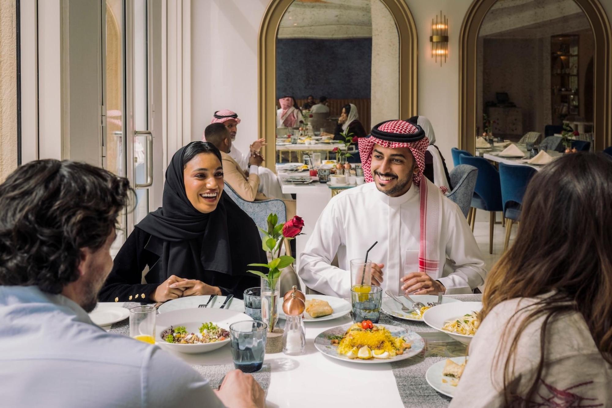 笑顔を浮かべ、レストランで一緒に食事をするグループ