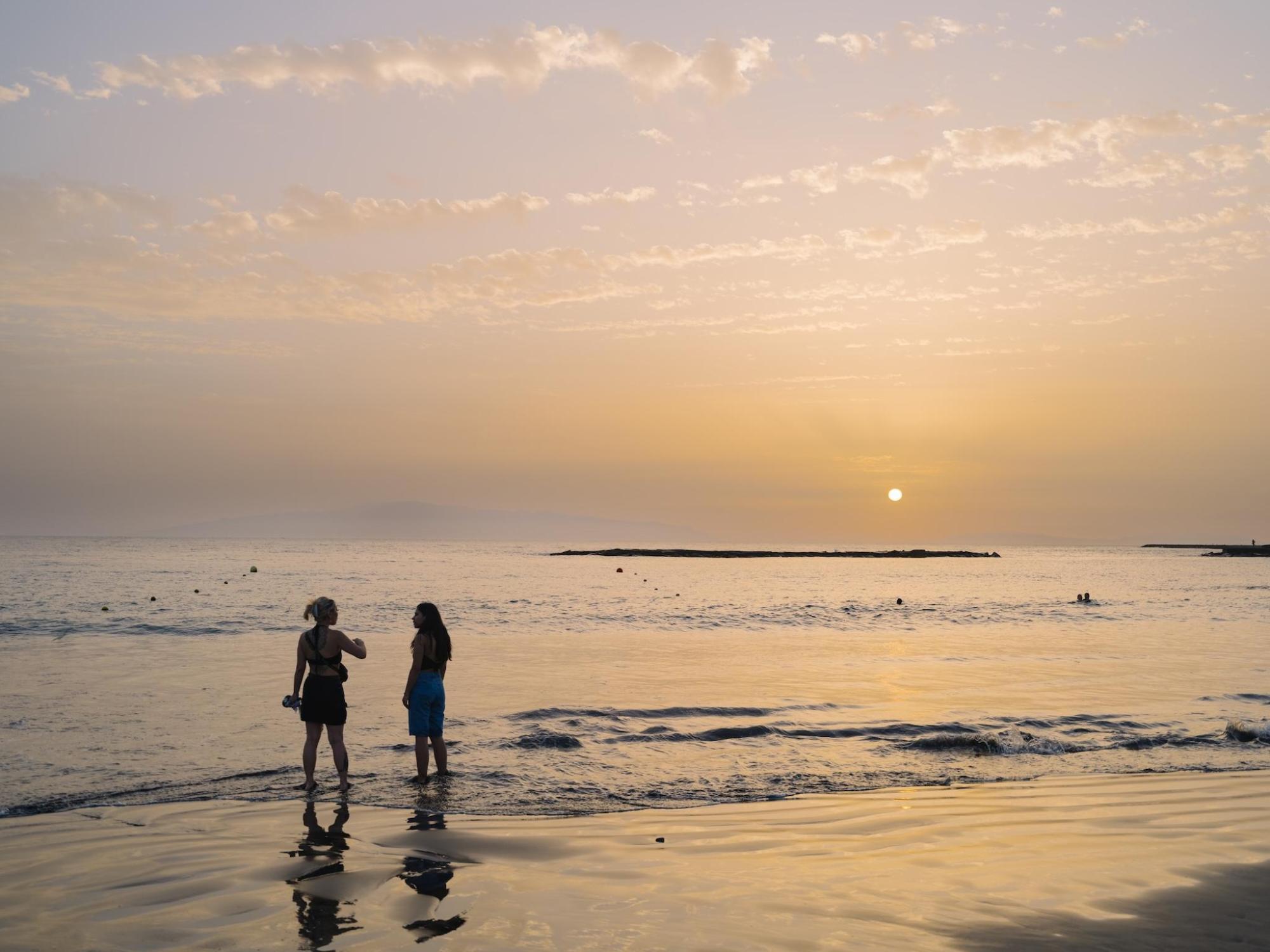 2 Personen stehen bei Sonnenuntergang an einem Privatstrand