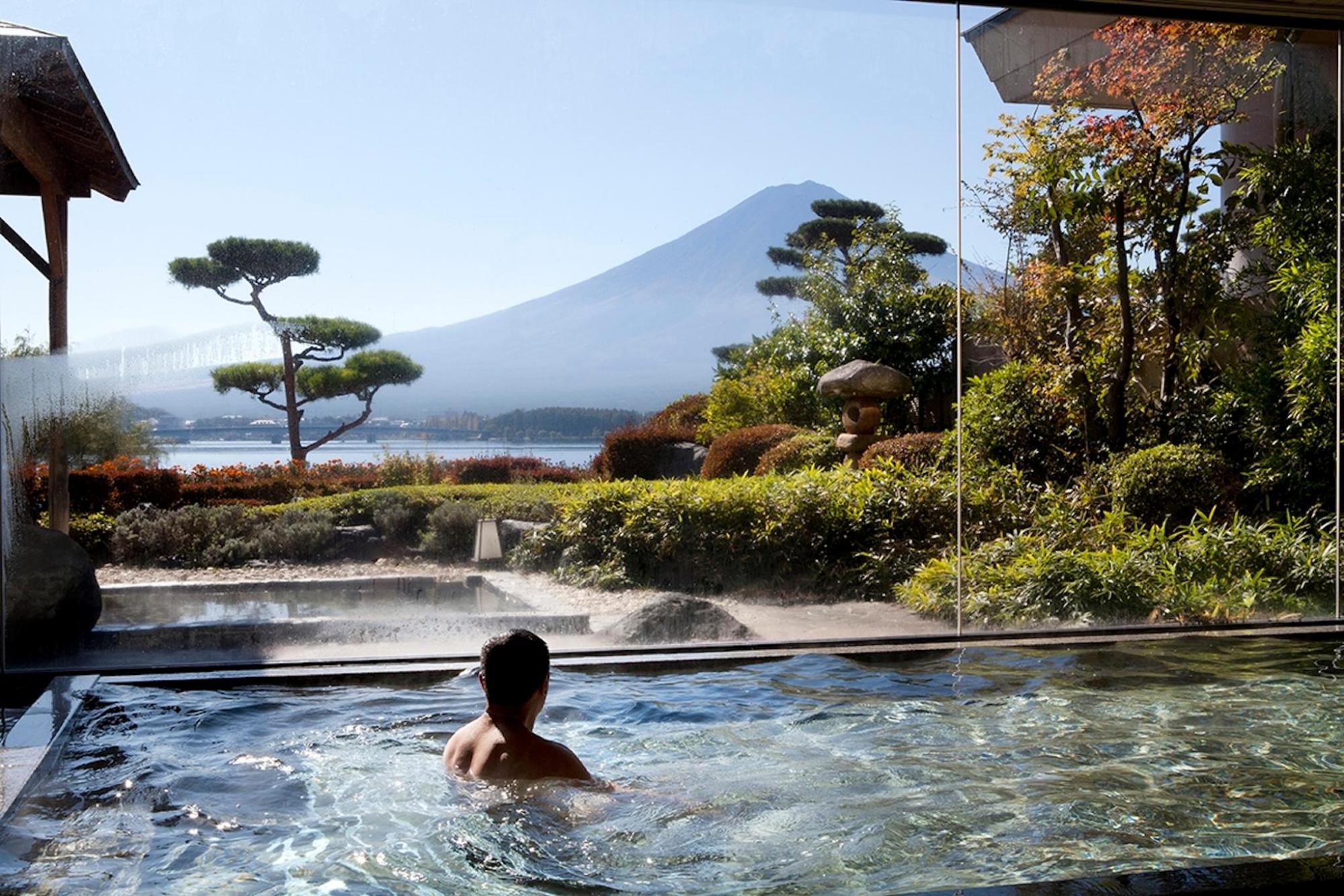 A man relaxes in an onsen with a mountain backdrop