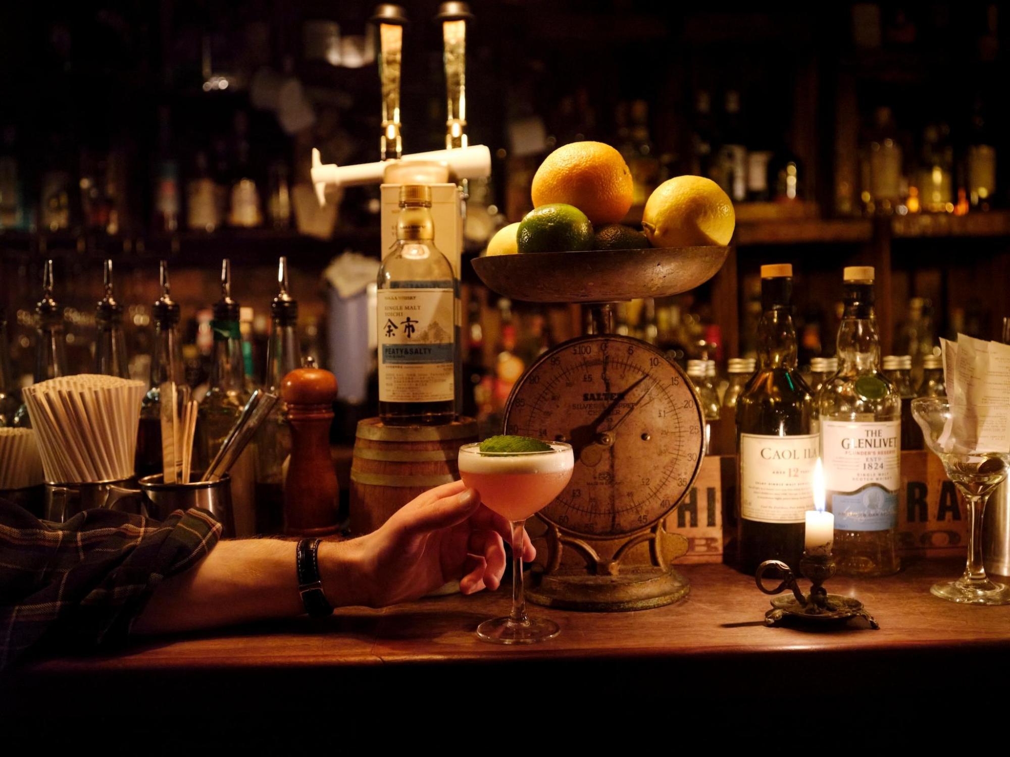 A bartender presenting a cocktail glass at a stylish bar