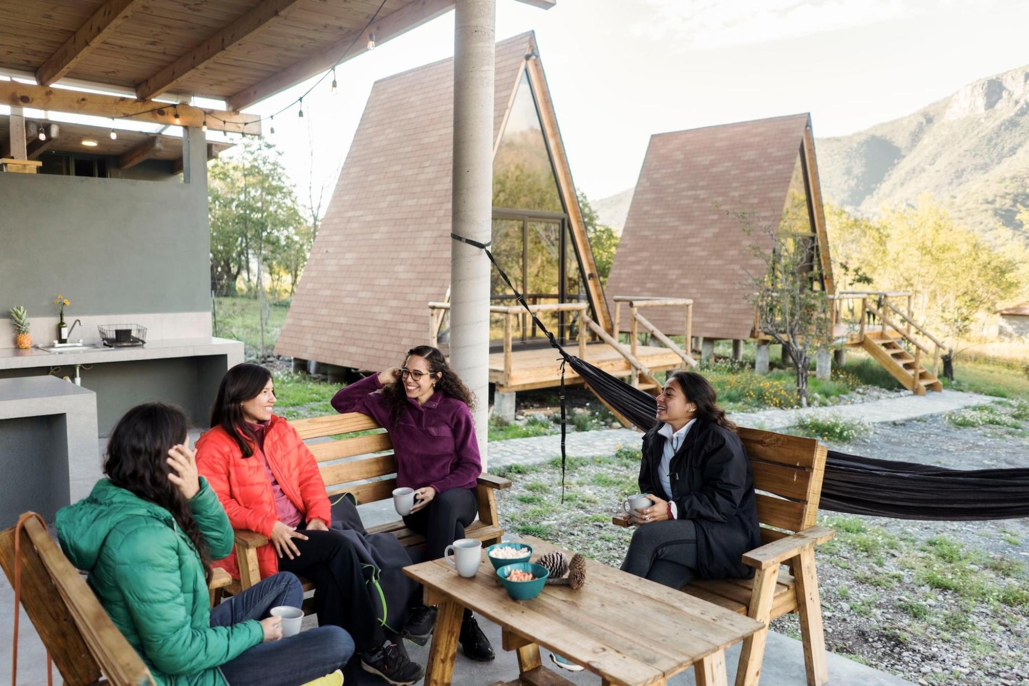 Four women relax and talk on a patio with hammocks