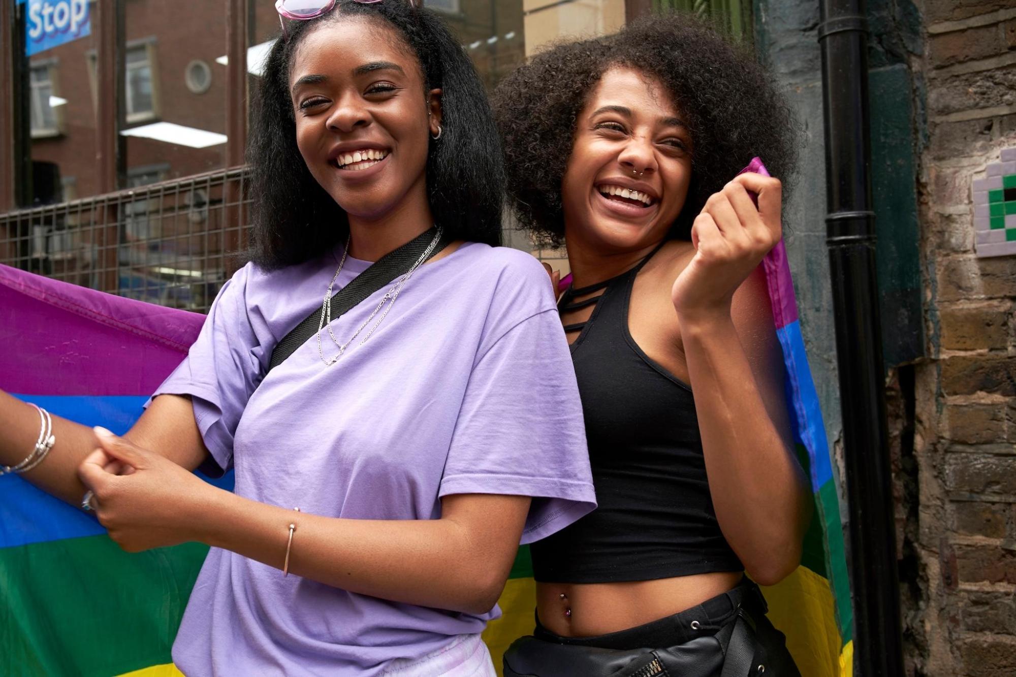  Two women proudly holding a rainbow Pride flag