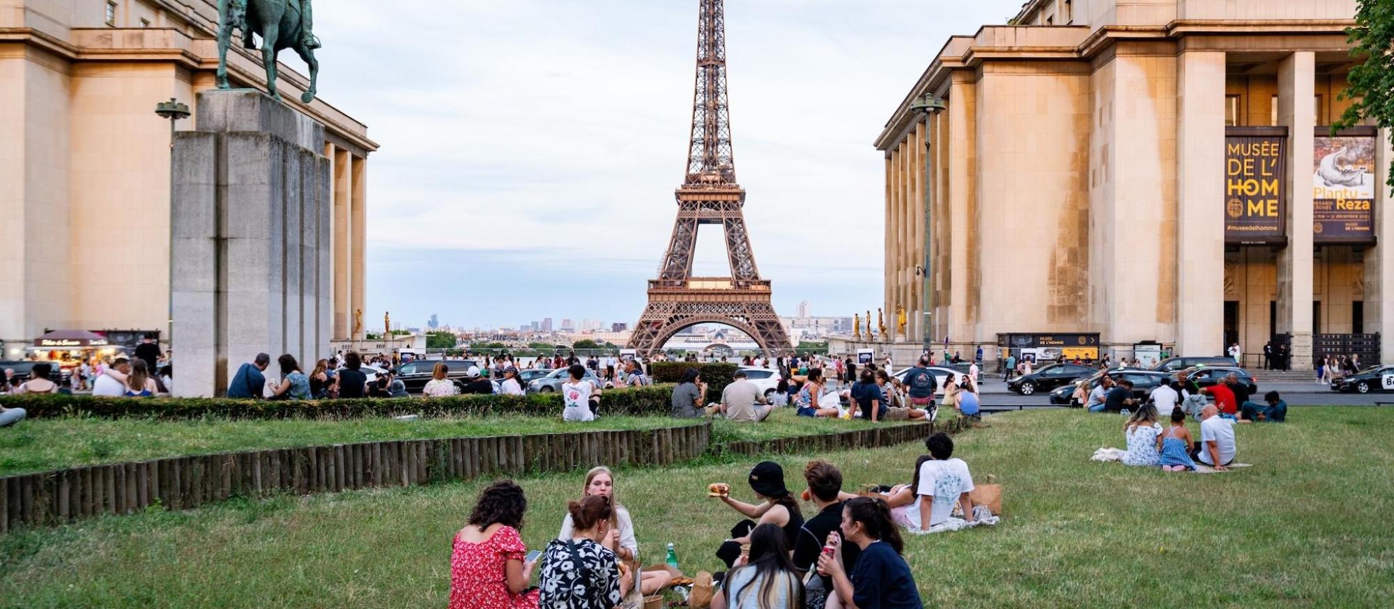 People sitting on the grass in front of the Eiffel Tower