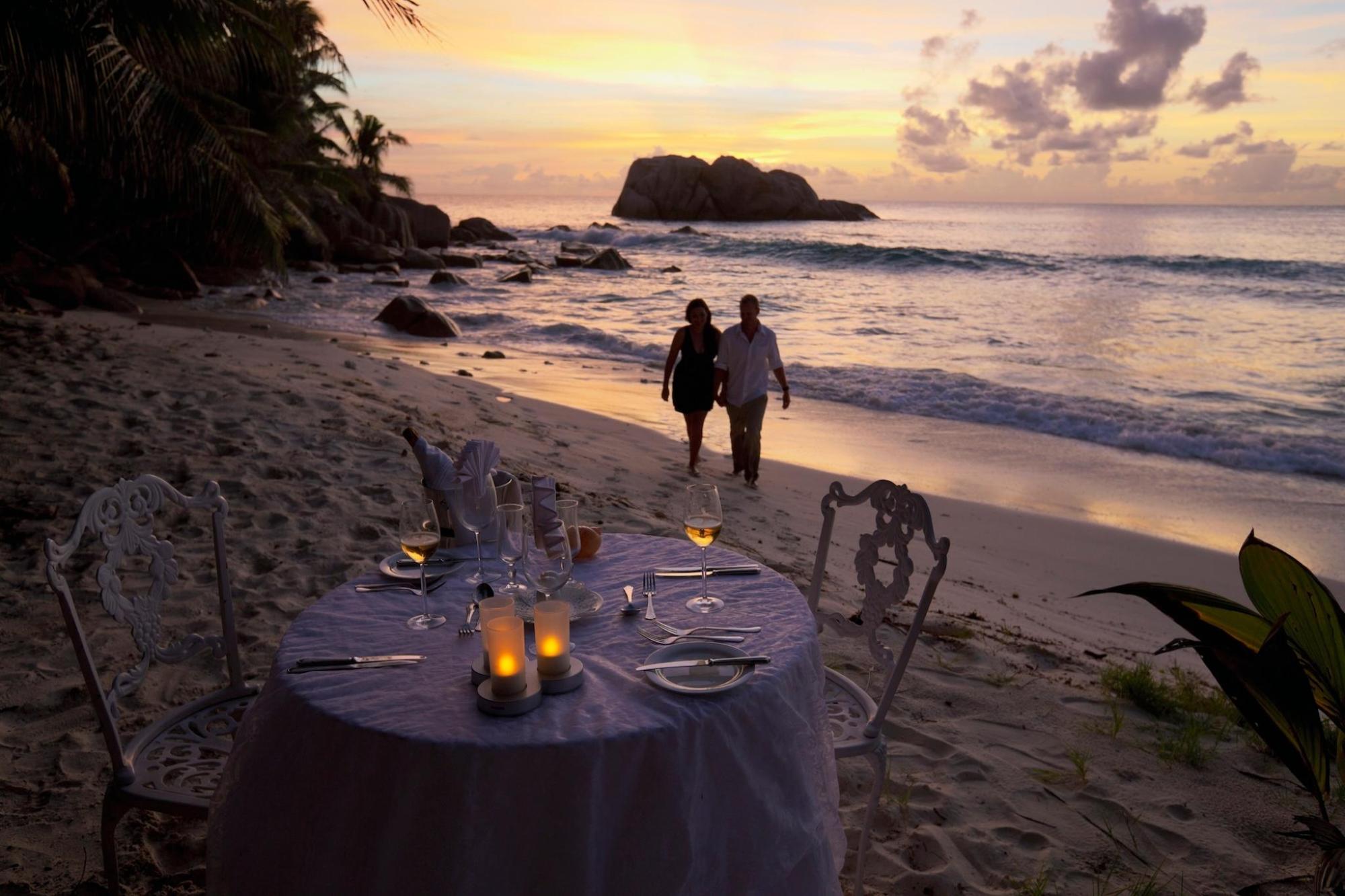 Two people standing on a private beach at sunset