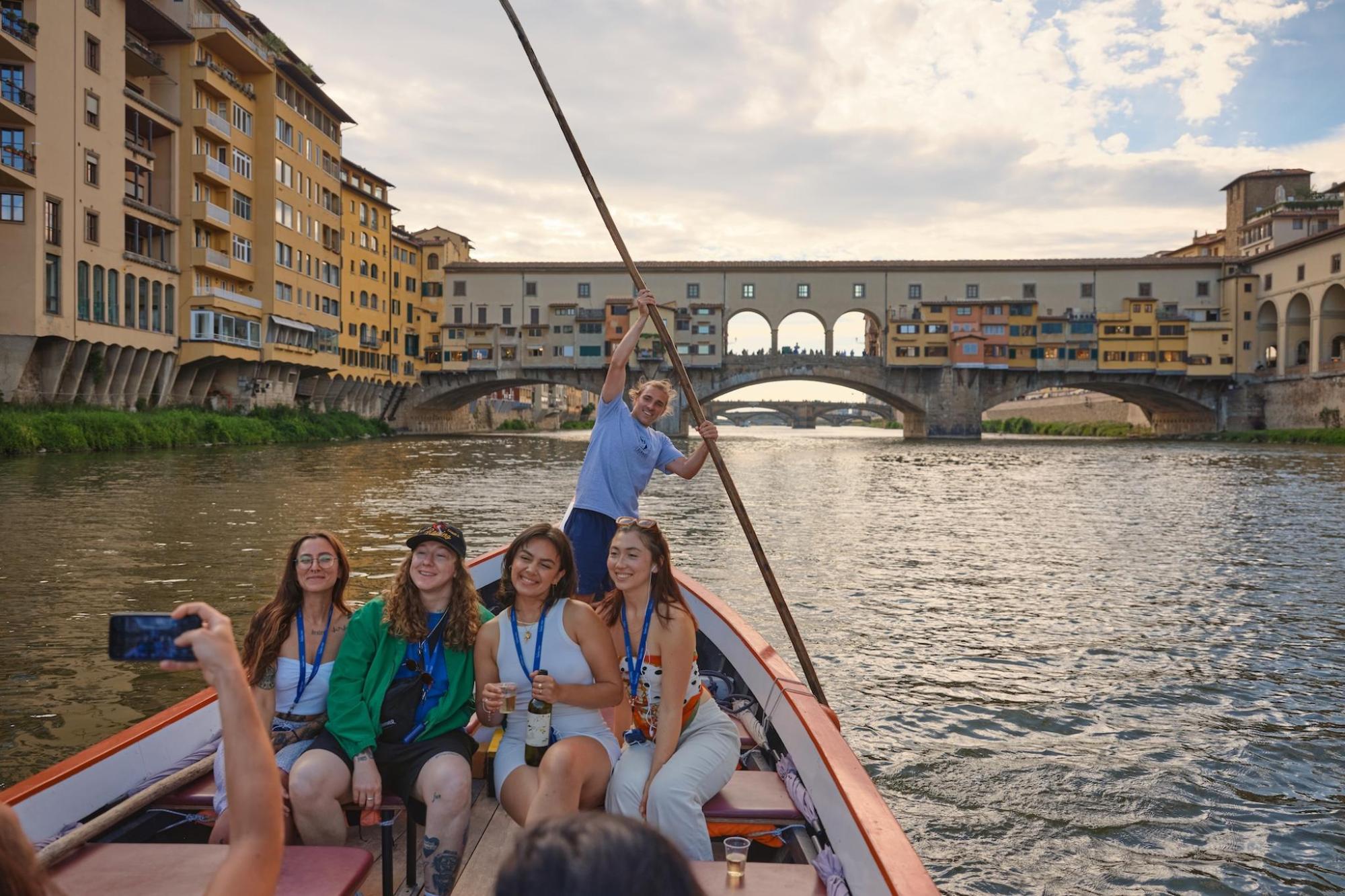 A group of friends enjoy a boat ride on a river in Florence