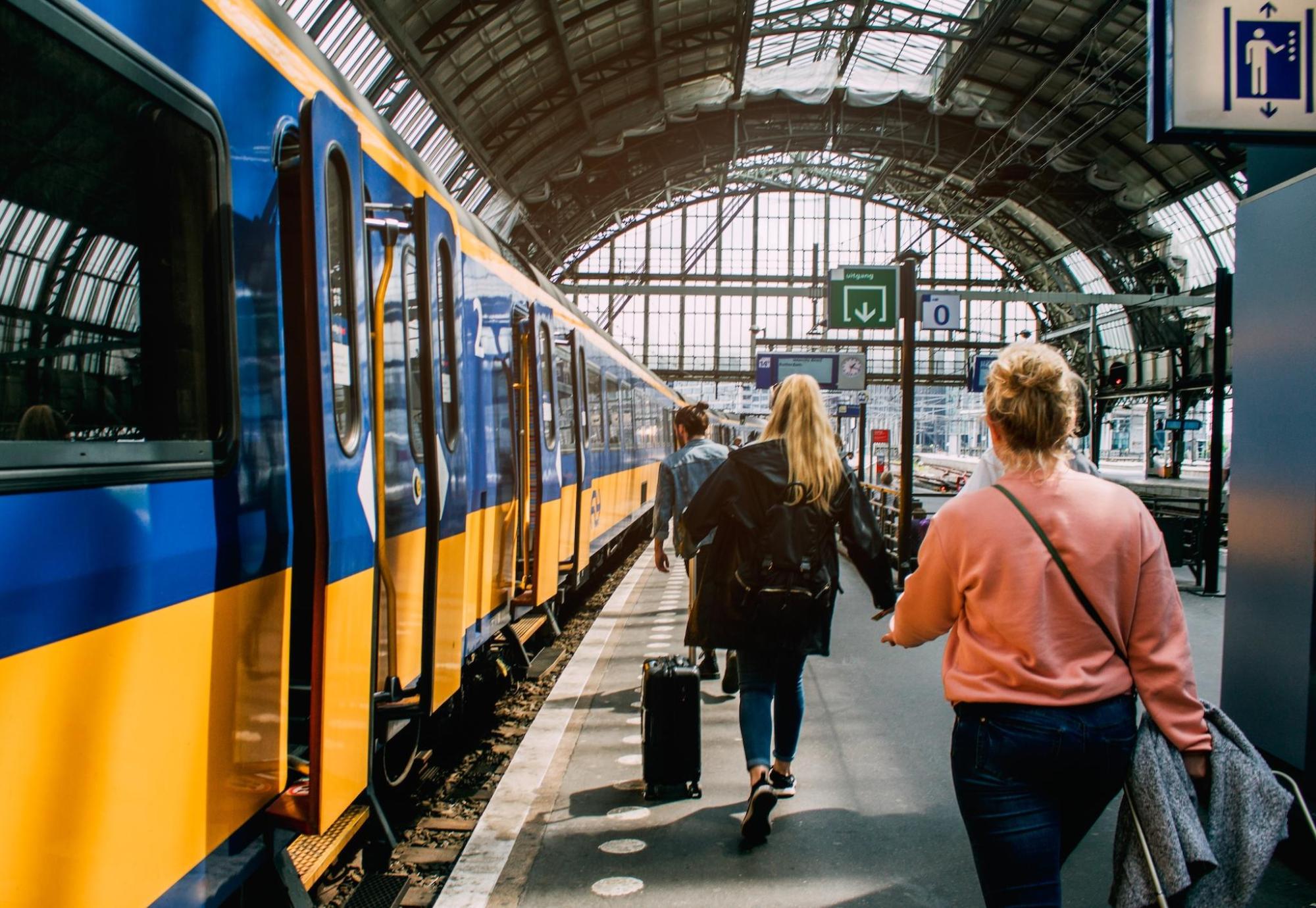 Three people walking towards a train at Centraal station