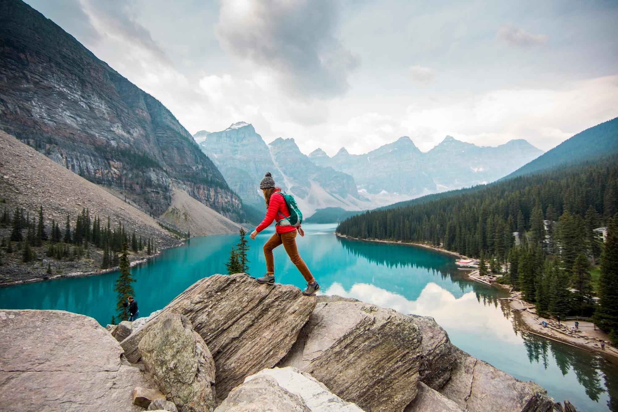  A woman stands on a rock, gazing at a serene lake in Banff