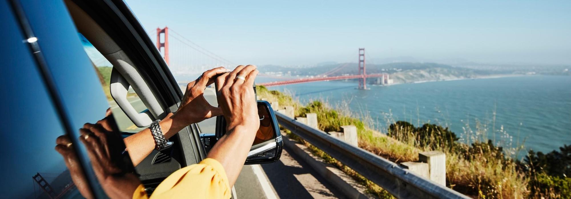Woman snaps photo from car, Golden Gate in background