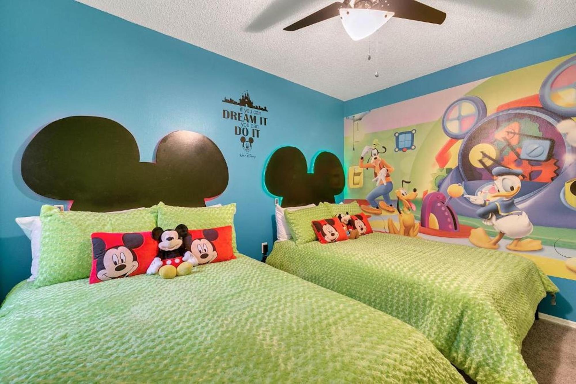 A Mickey Mouse themed bedroom featuring two twin beds
