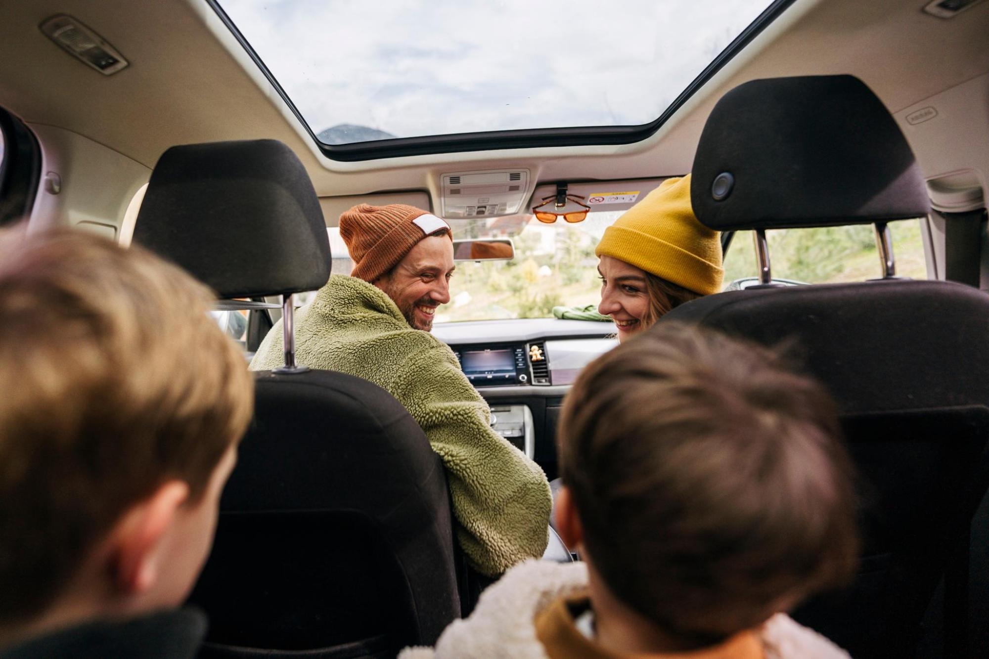A smiling family of four sitting together in a car