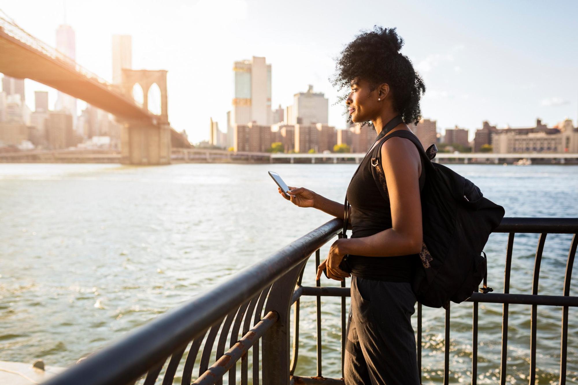 A woman holds her phone while looking at NYC's landscape