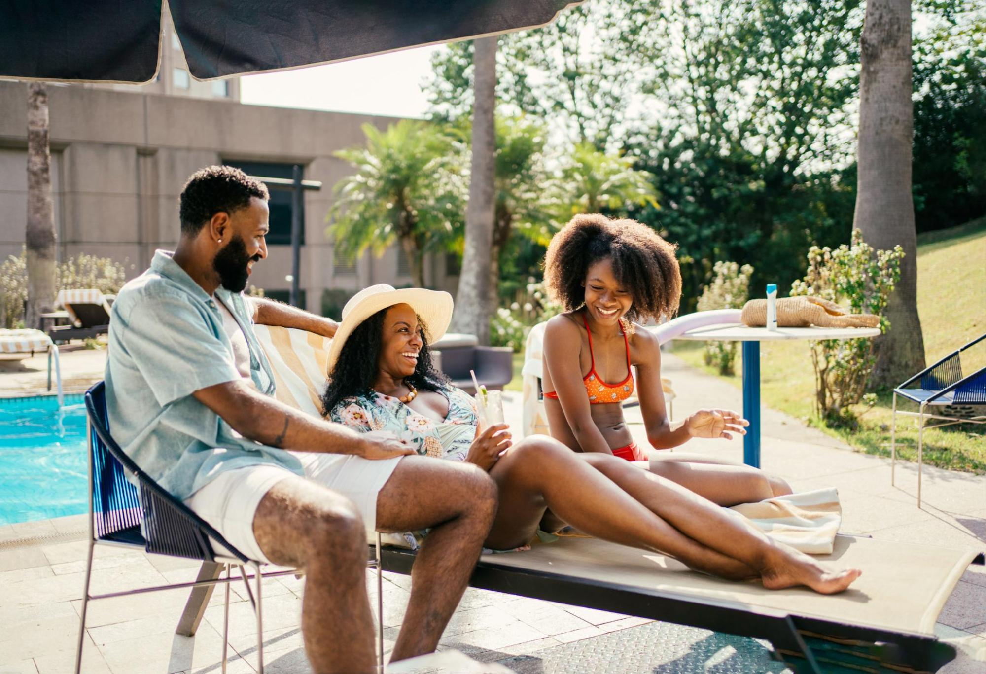 Three friends enjoy a lounge chair by the pool