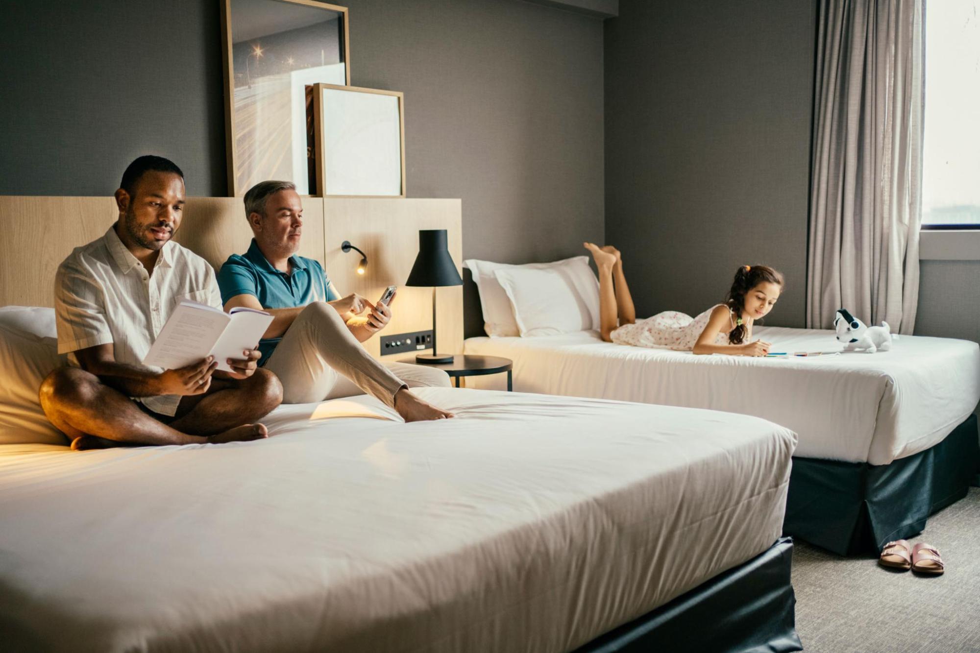 A family sitting on their beds in their hotel room