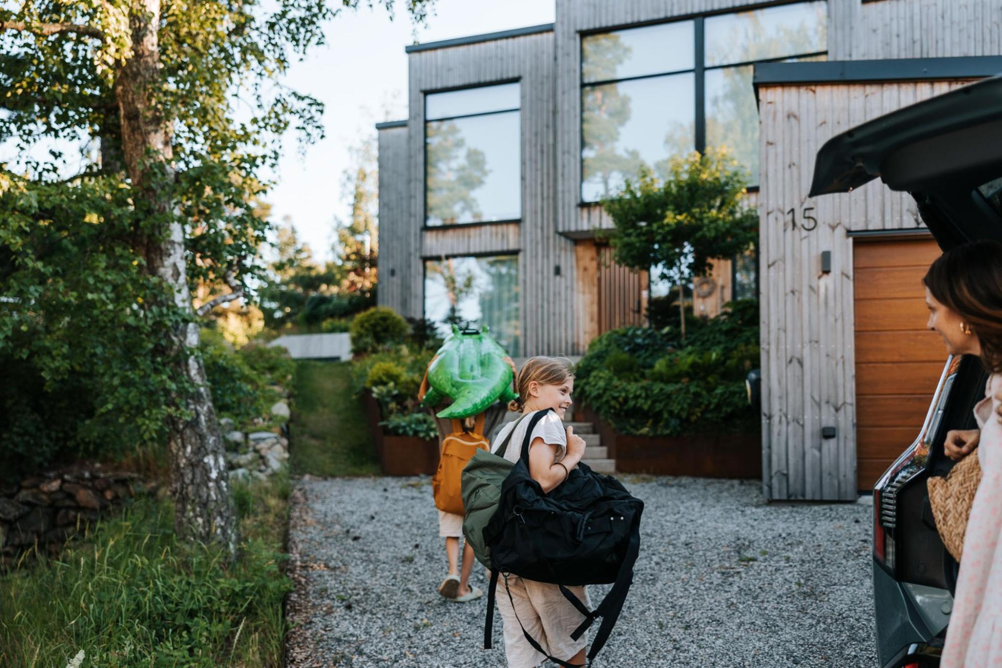A family carrying their bags and walking to a holiday home