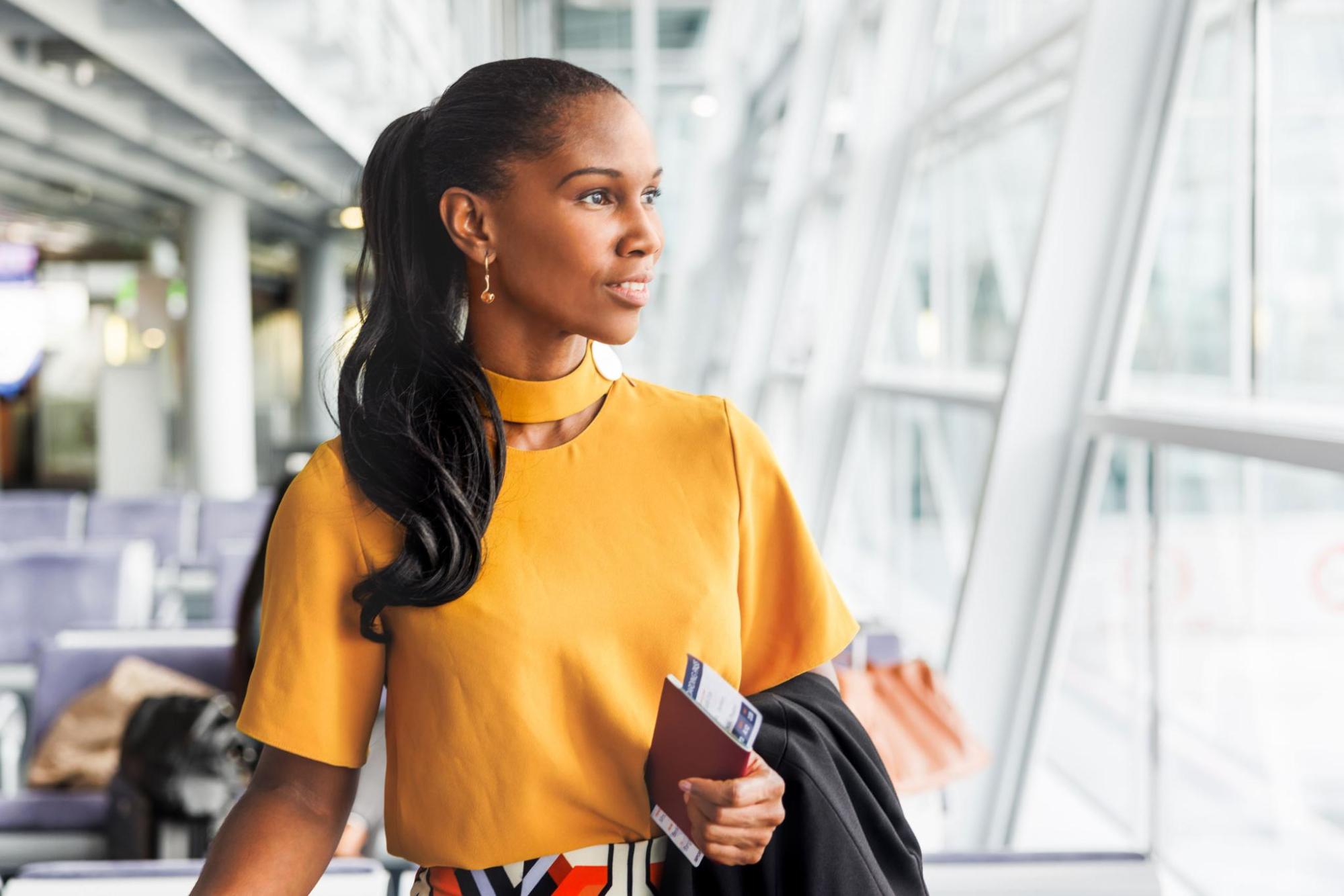 Woman at airport holding passport and boarding pass