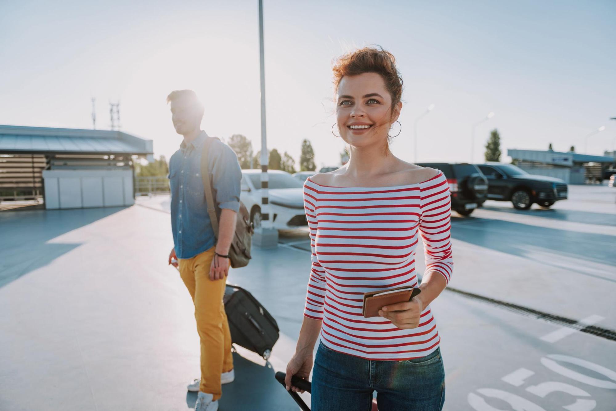 Woman with passport at airport parking, ready to travel soon