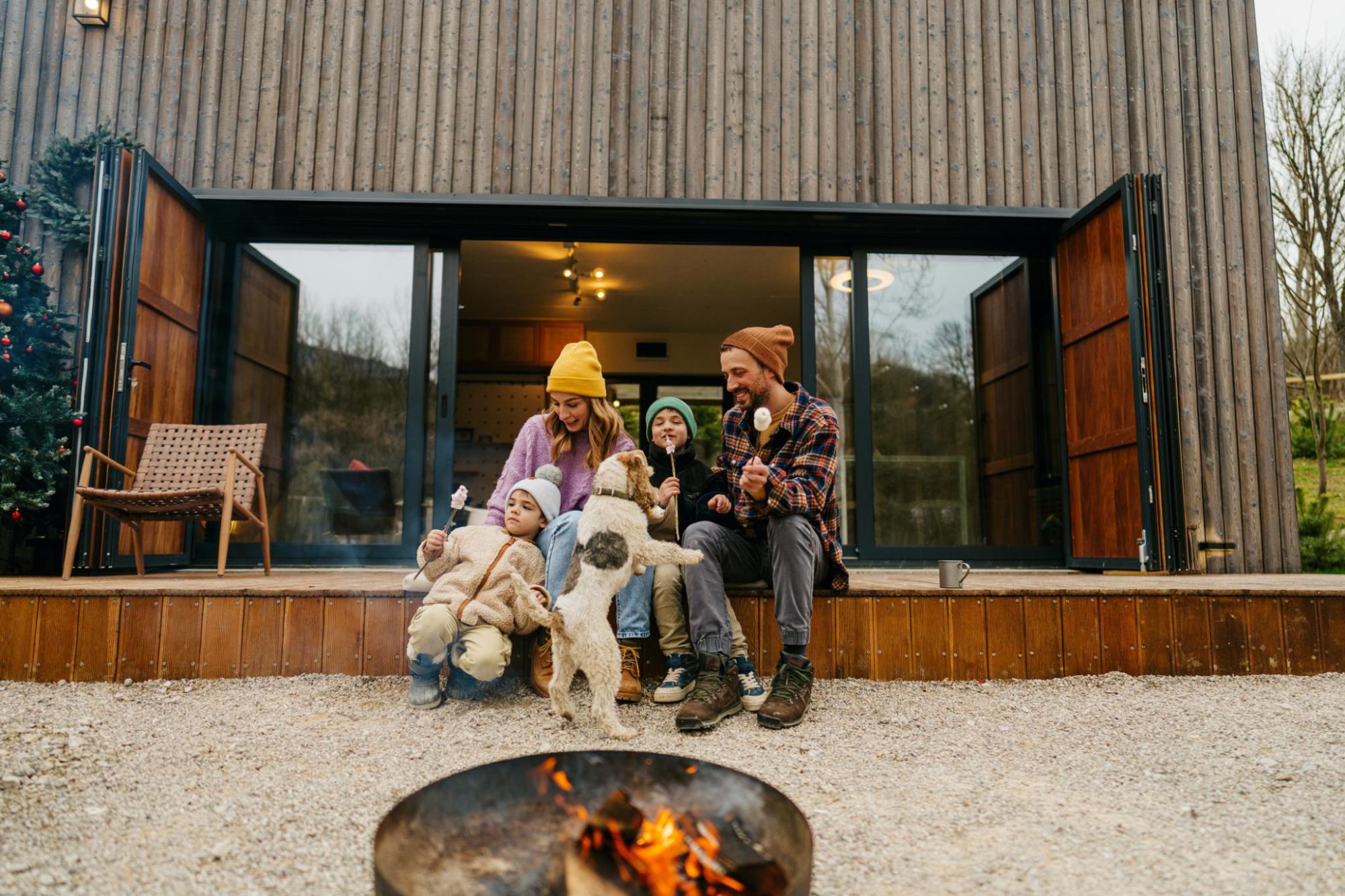 Family packing suitcase while kids play with dog on bed