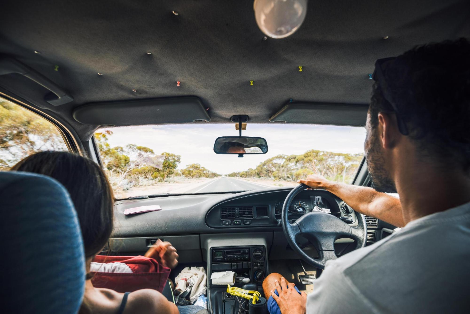 A man and woman happily driving together in a car.
