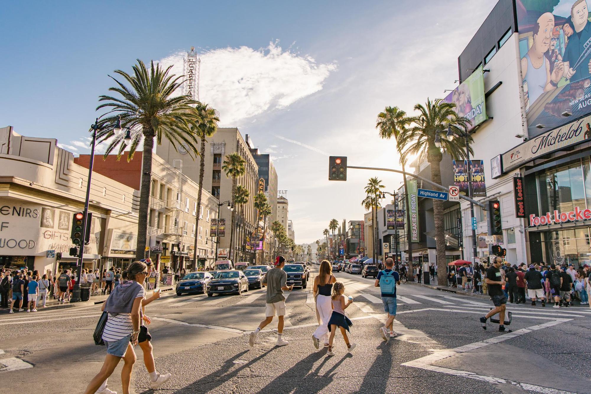People crossing Hollywood Boulevard lined with palm trees