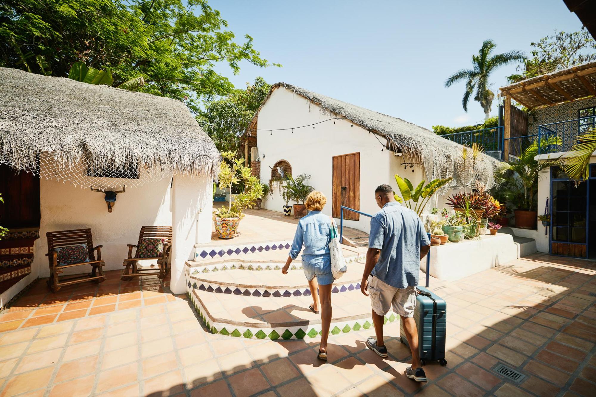 Couple strolling through a charming thatched-roof courtyard