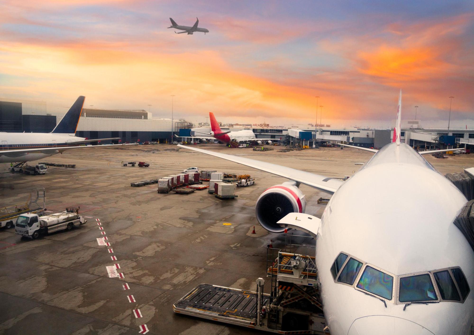 Airplanes parked at airport terminal at sunset