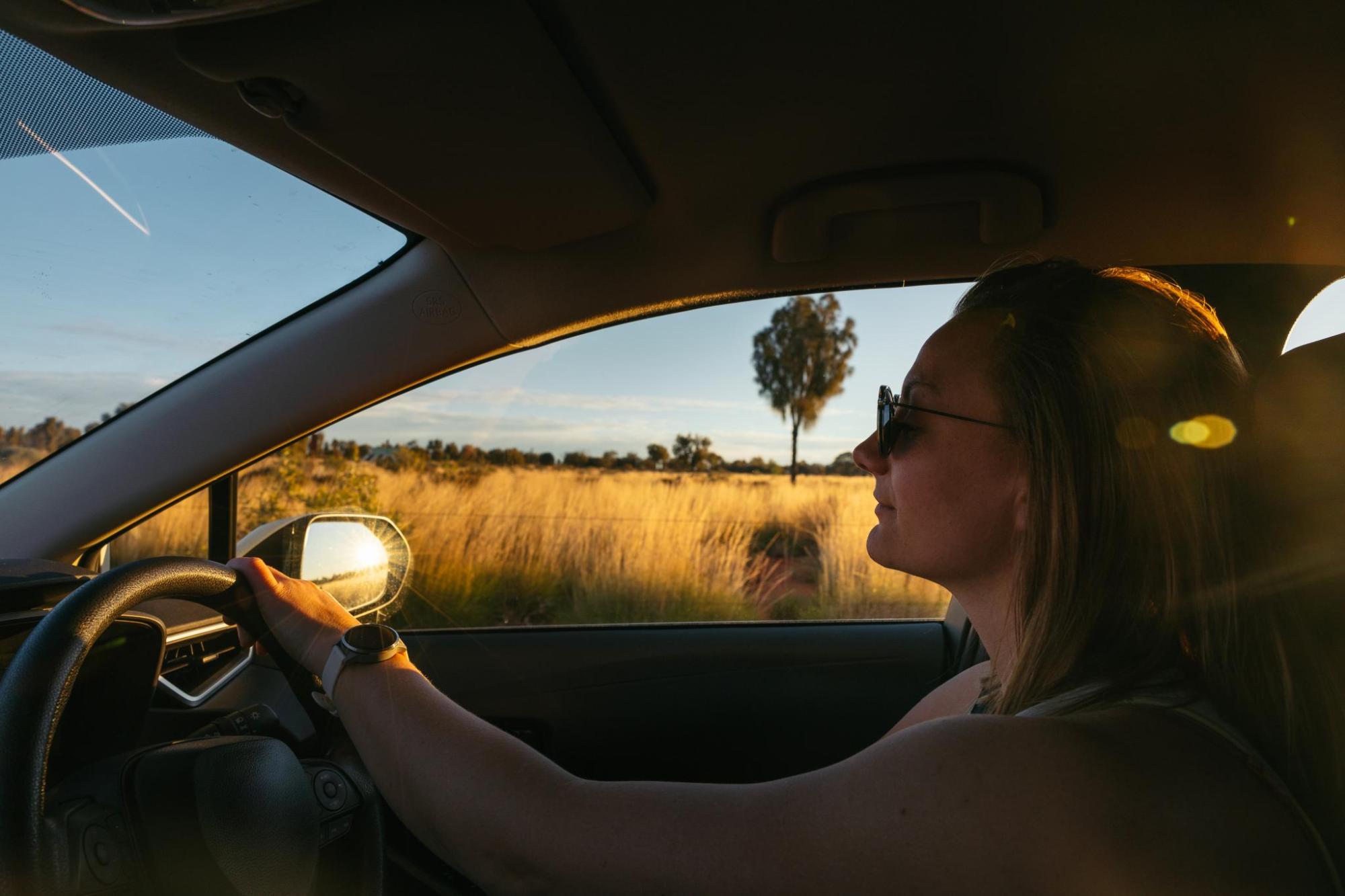 Driver inside car on Australian road at sunset