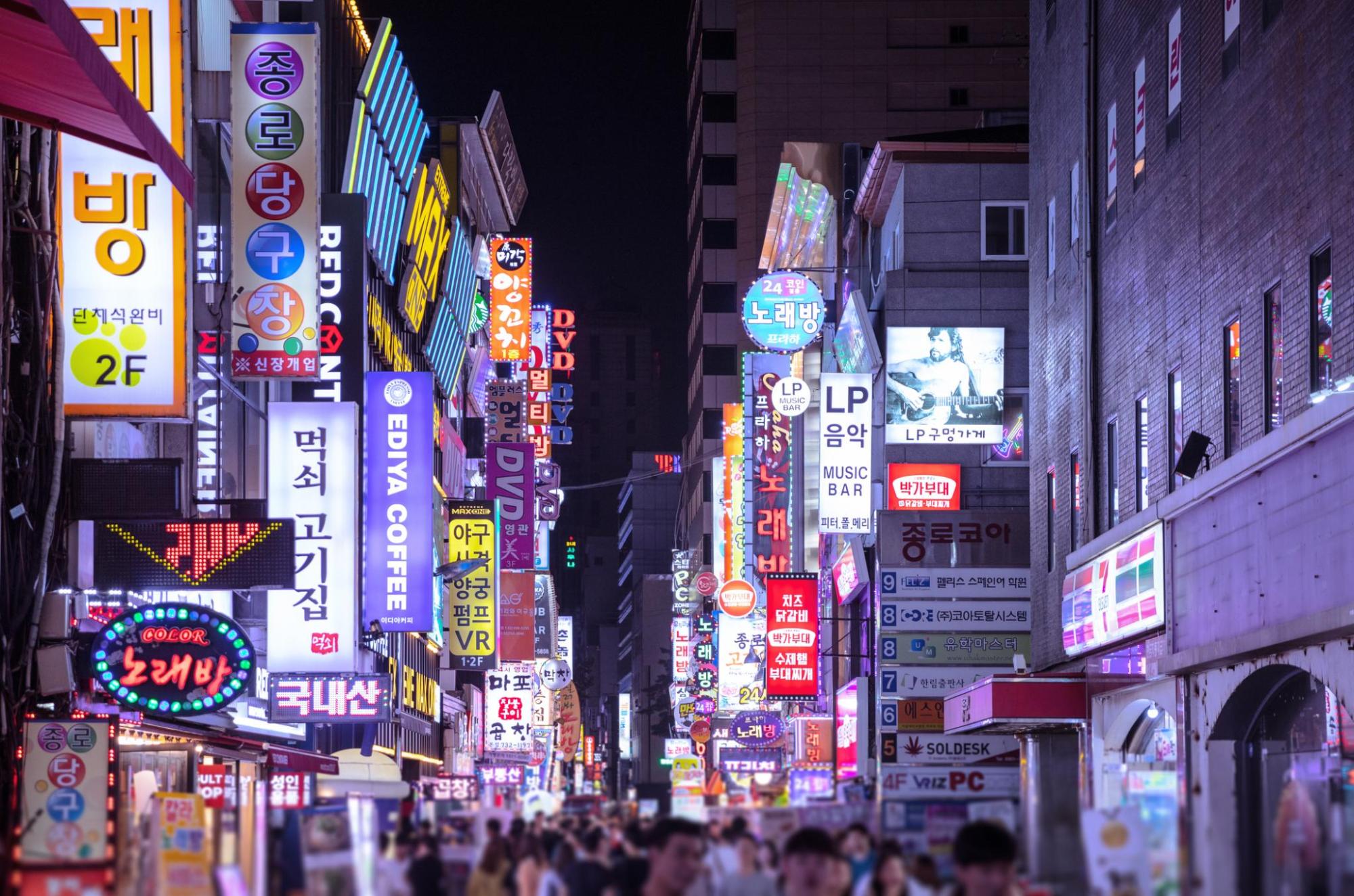 A bustling Seoul street at night, filled with people walking