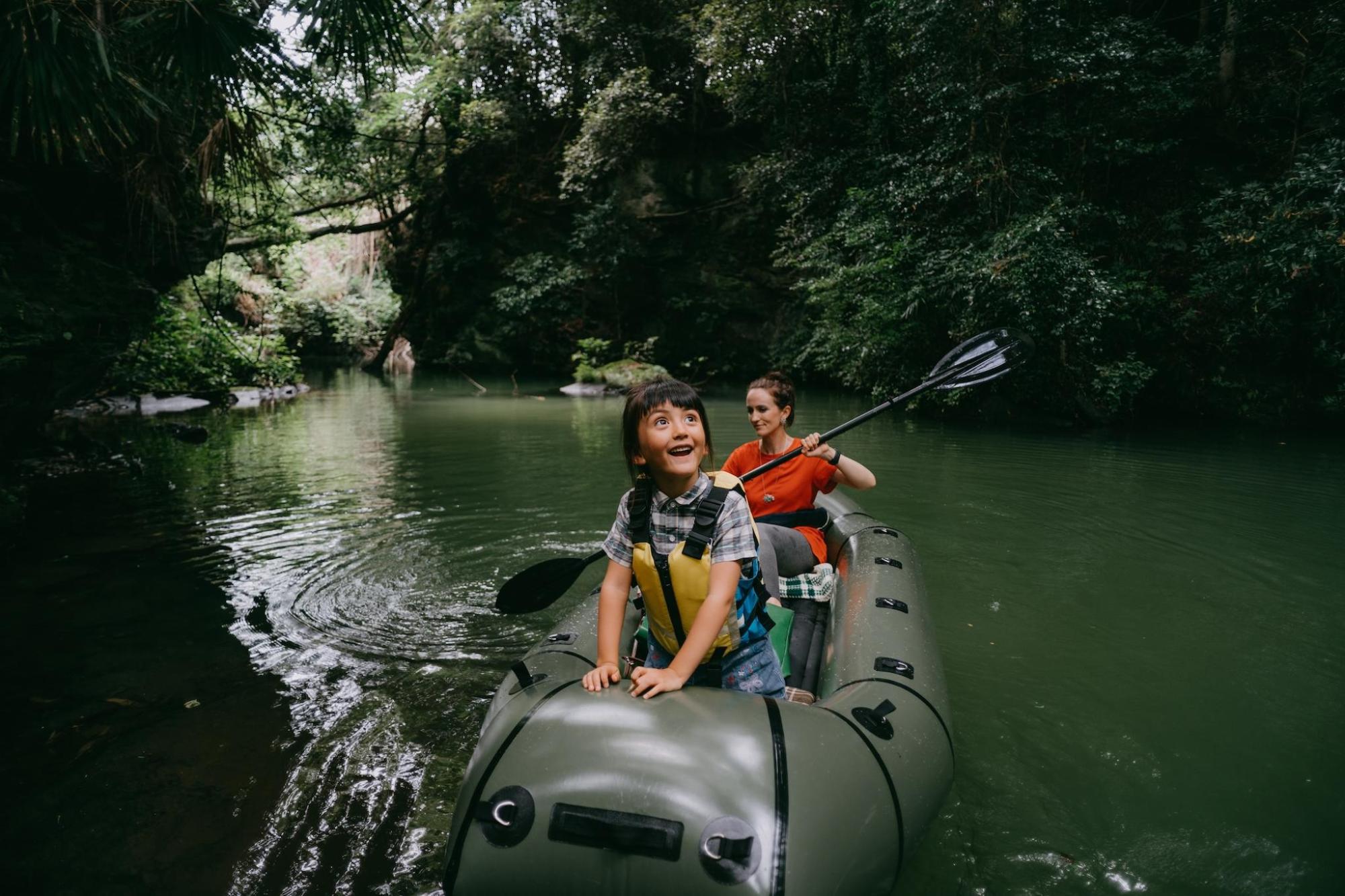 A girl haves fun on inflatable raft with her mum in a forest