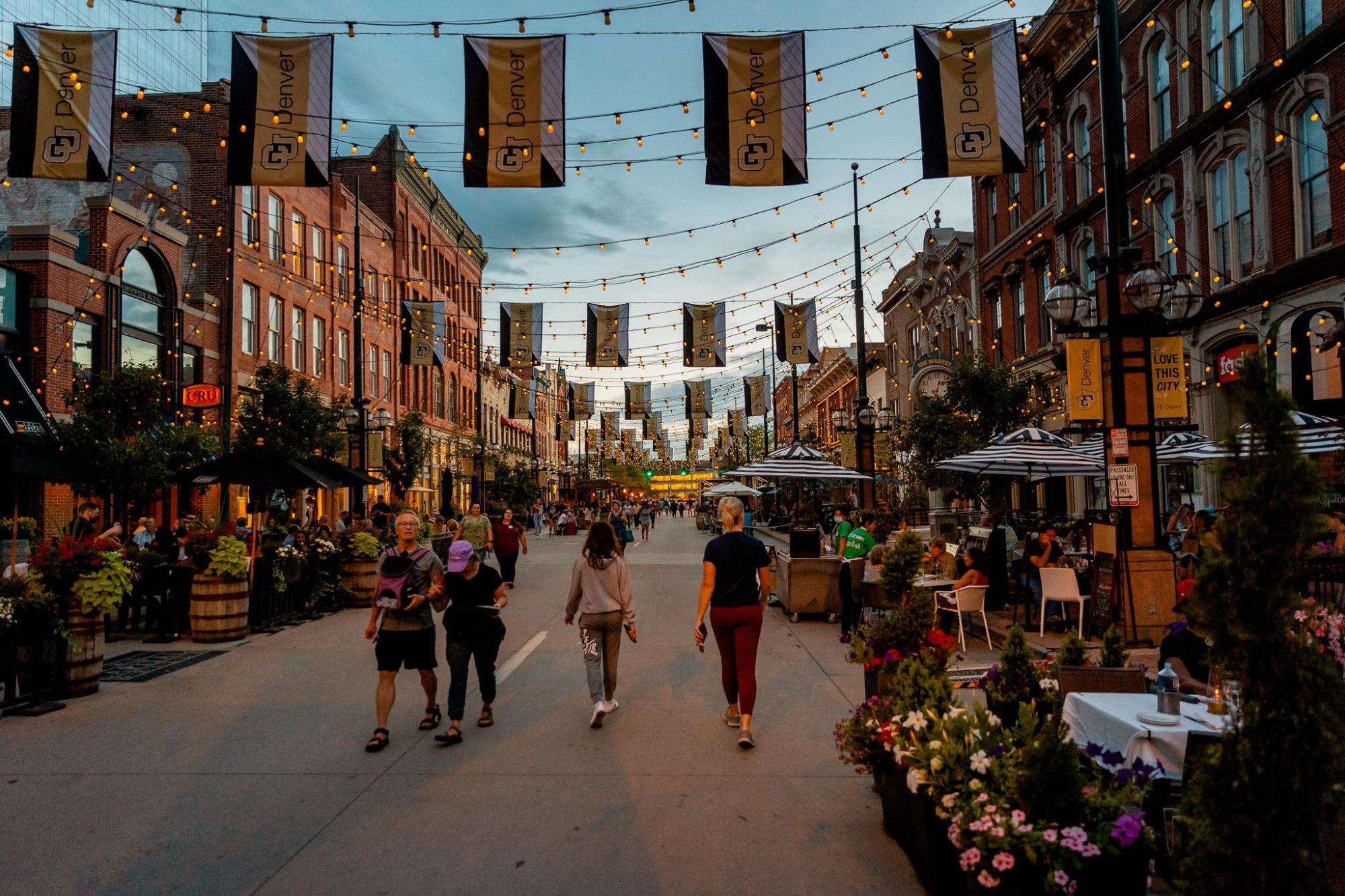 People walking on a lively LoDo street with string lights.