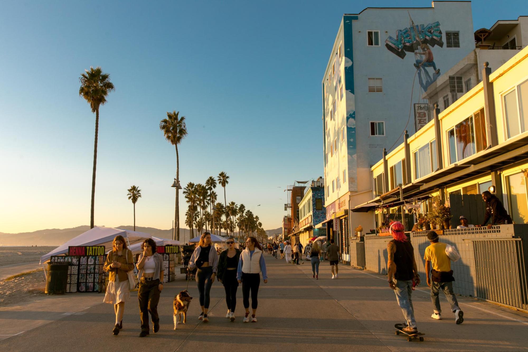 Venice Beach boardwalk at sunset with palm trees and people