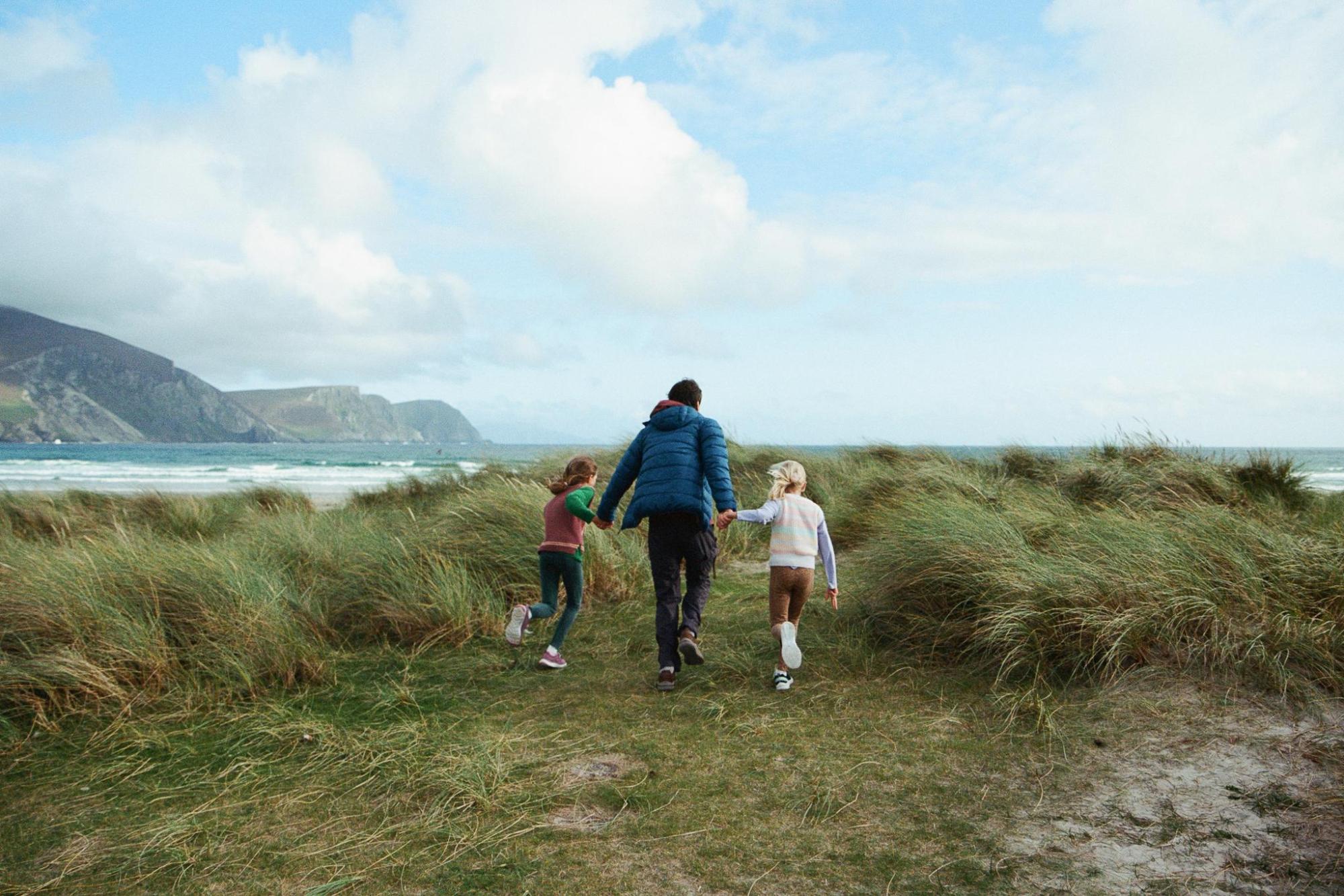 A father and his children trekking through grasslands