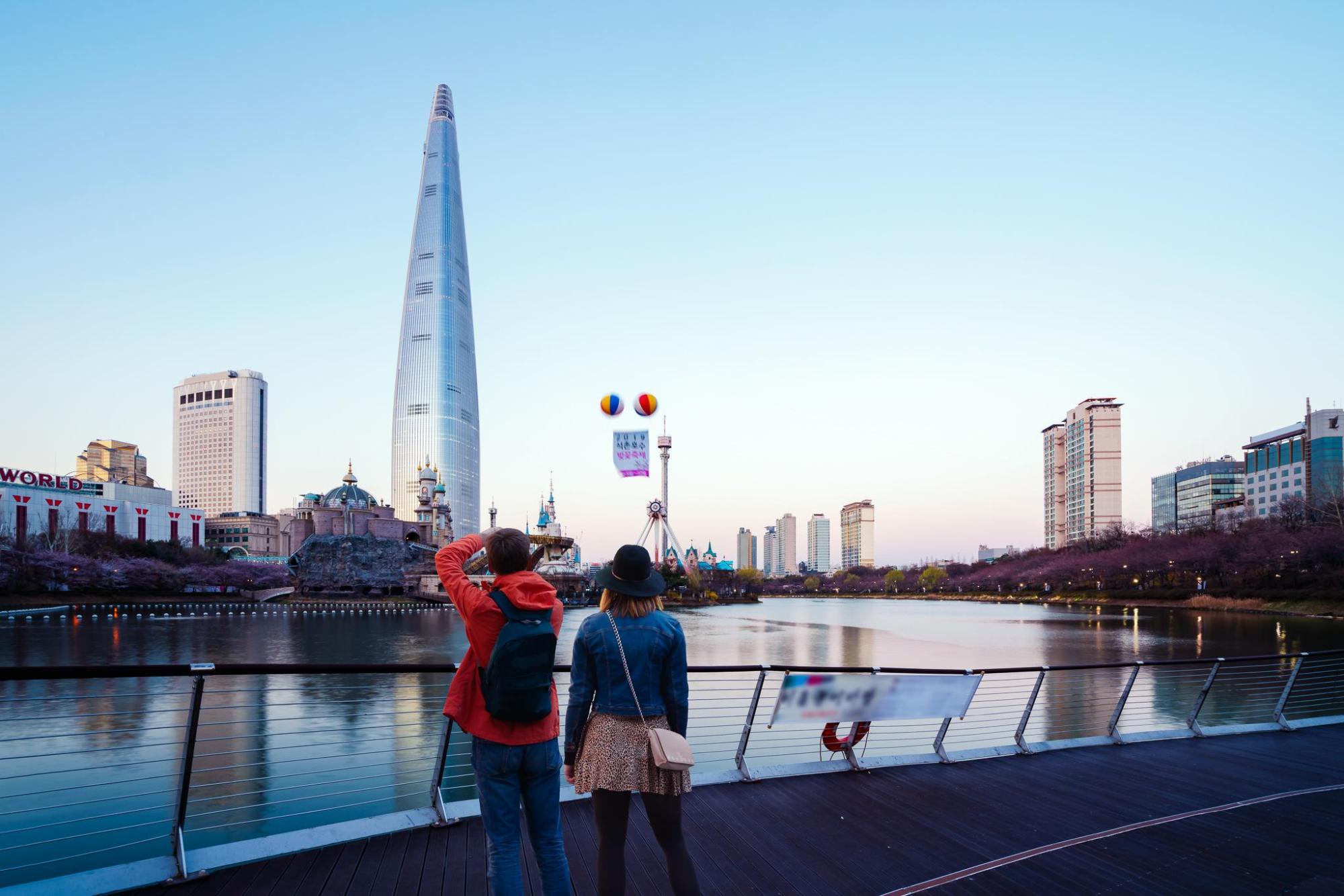 Two people on a Seoul boardwalk amid the city skyline