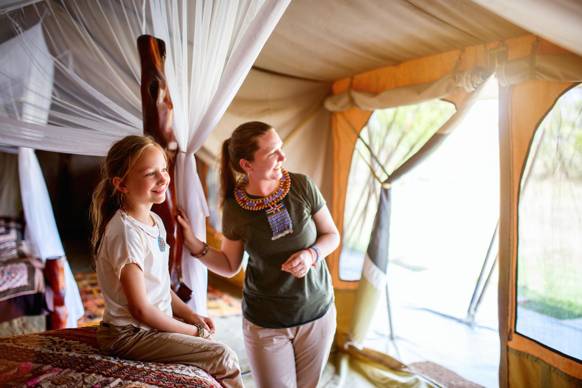 A mother and daughter smile in a safari tent