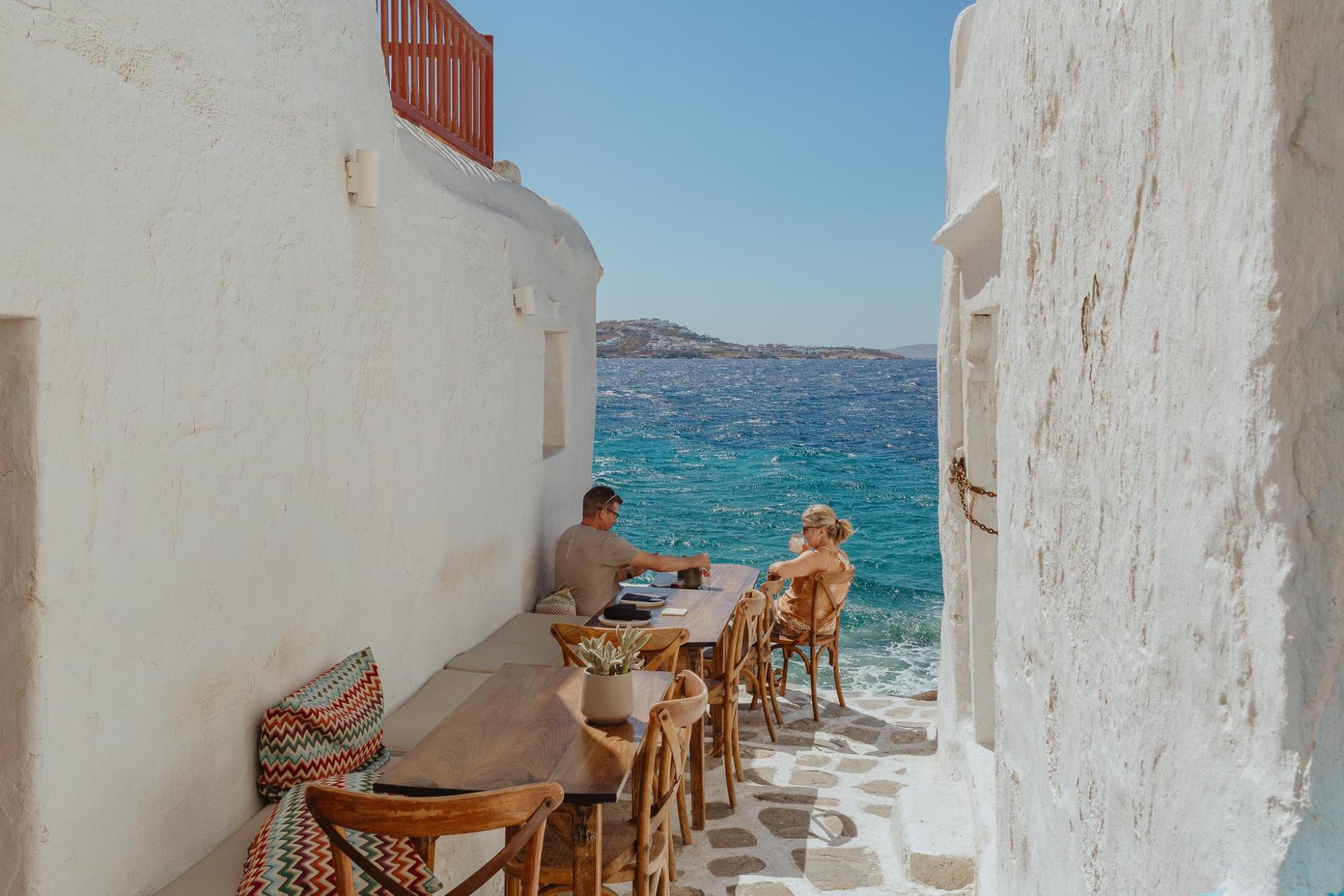 A couple sat at a table down an alley with a sea view