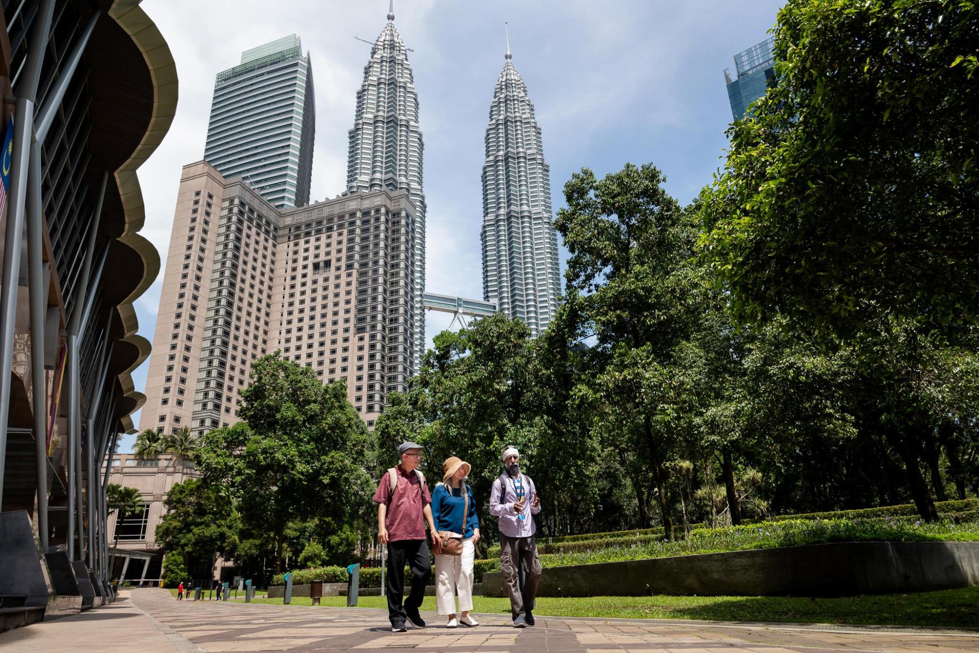 People walking in a park with the Petronas Twin Towers