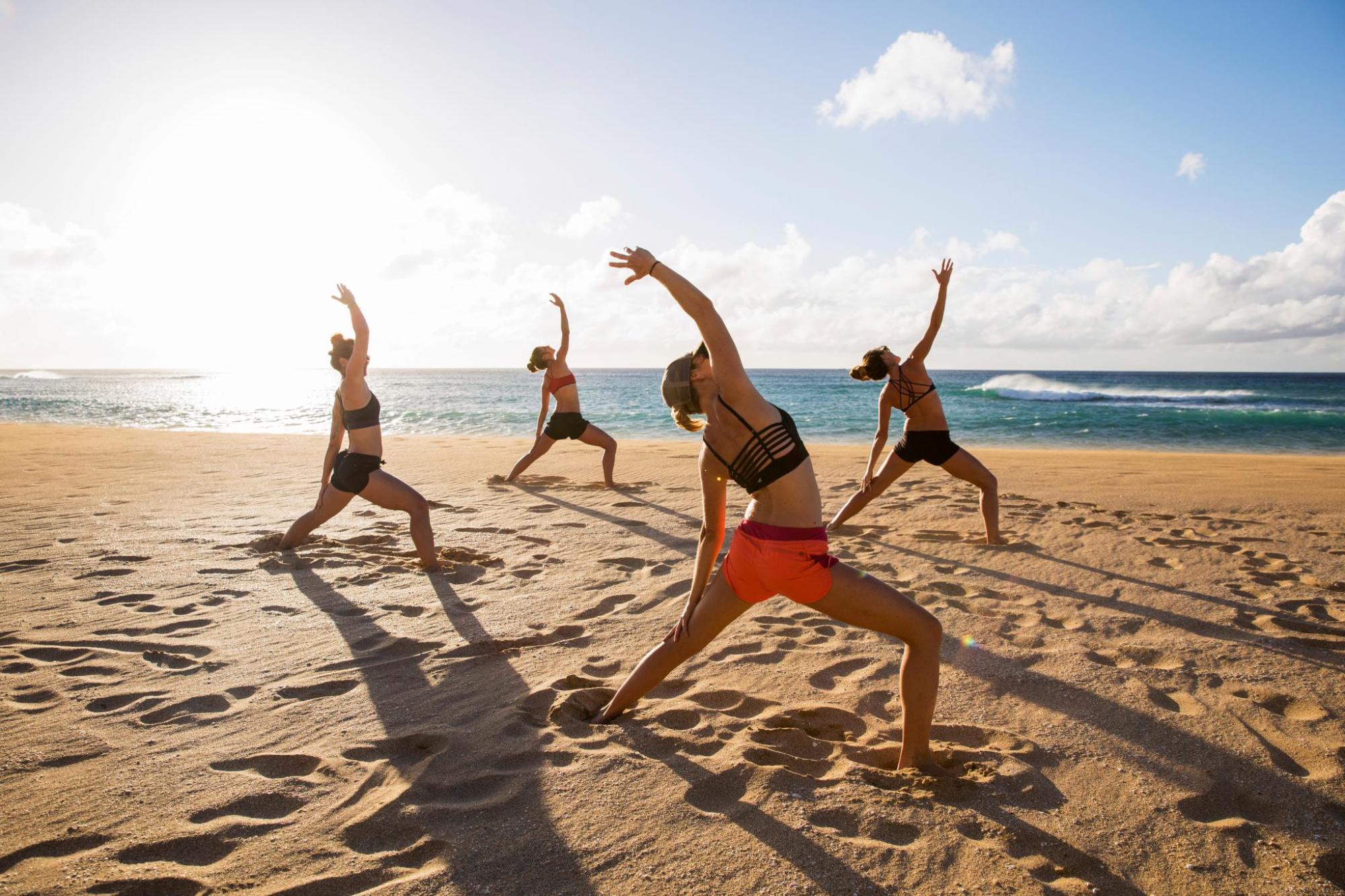 Un gruppo di persone che pratica yoga sulla spiaggia.