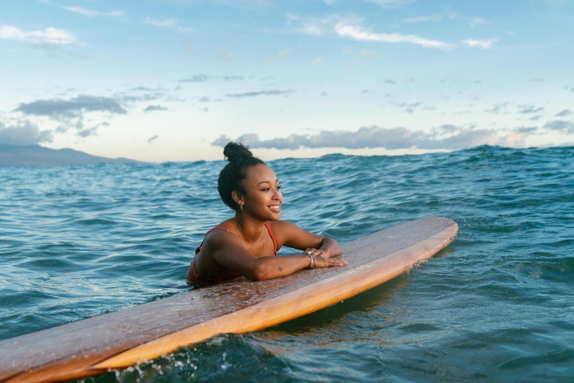 Woman lying on a surfboard in the ocean smiling