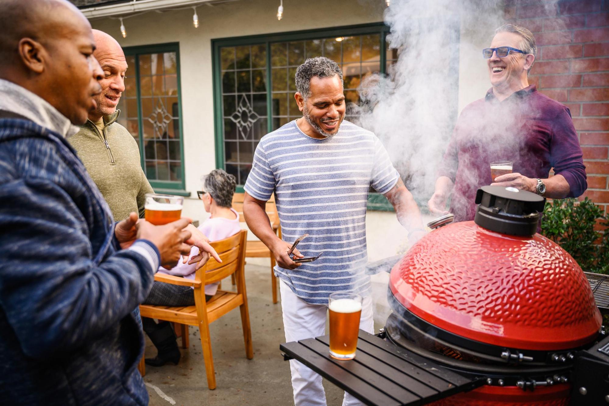 Friends grilling food and chatting outdoors with drinks