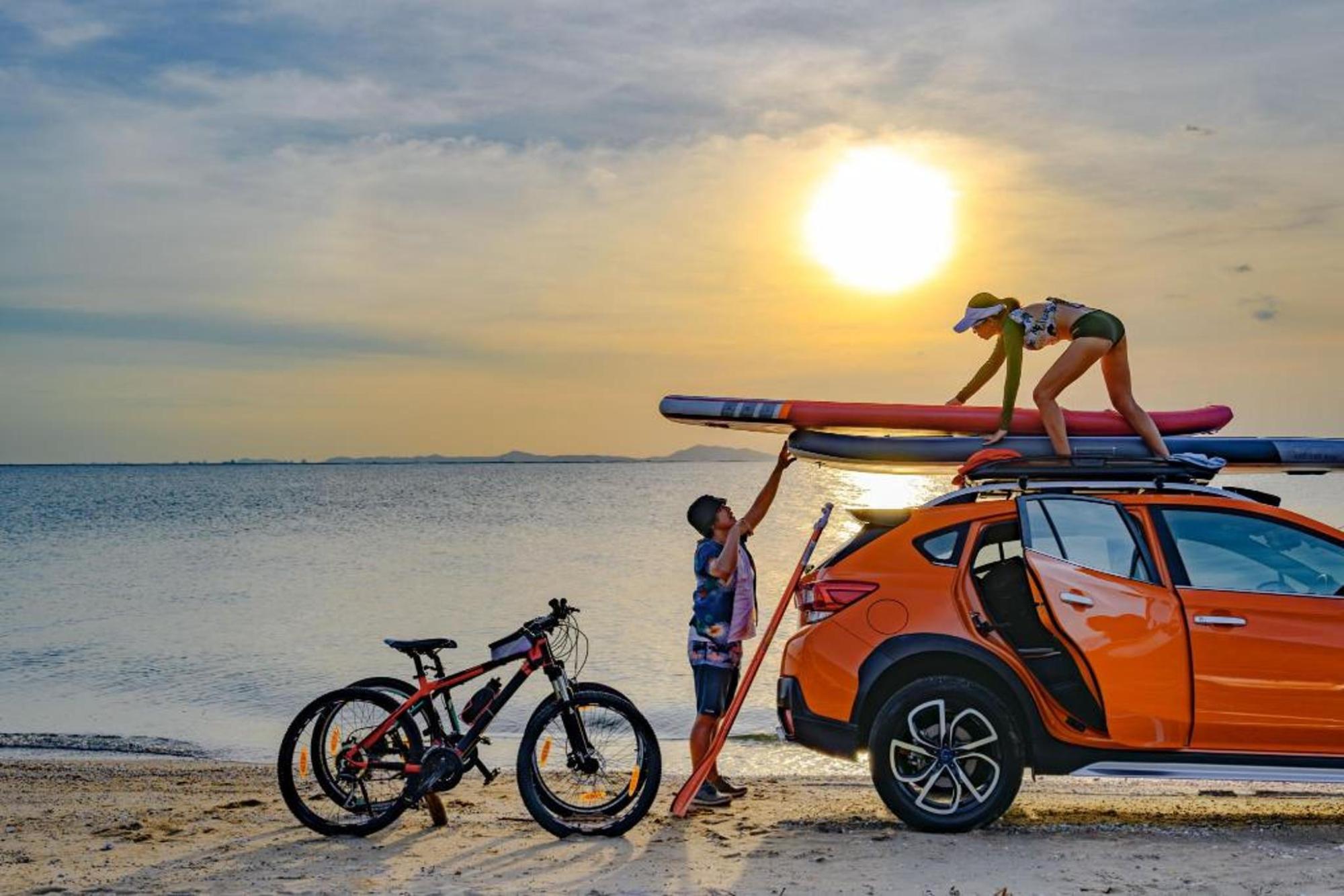 A couple loading sporting equipment to the roof of their car