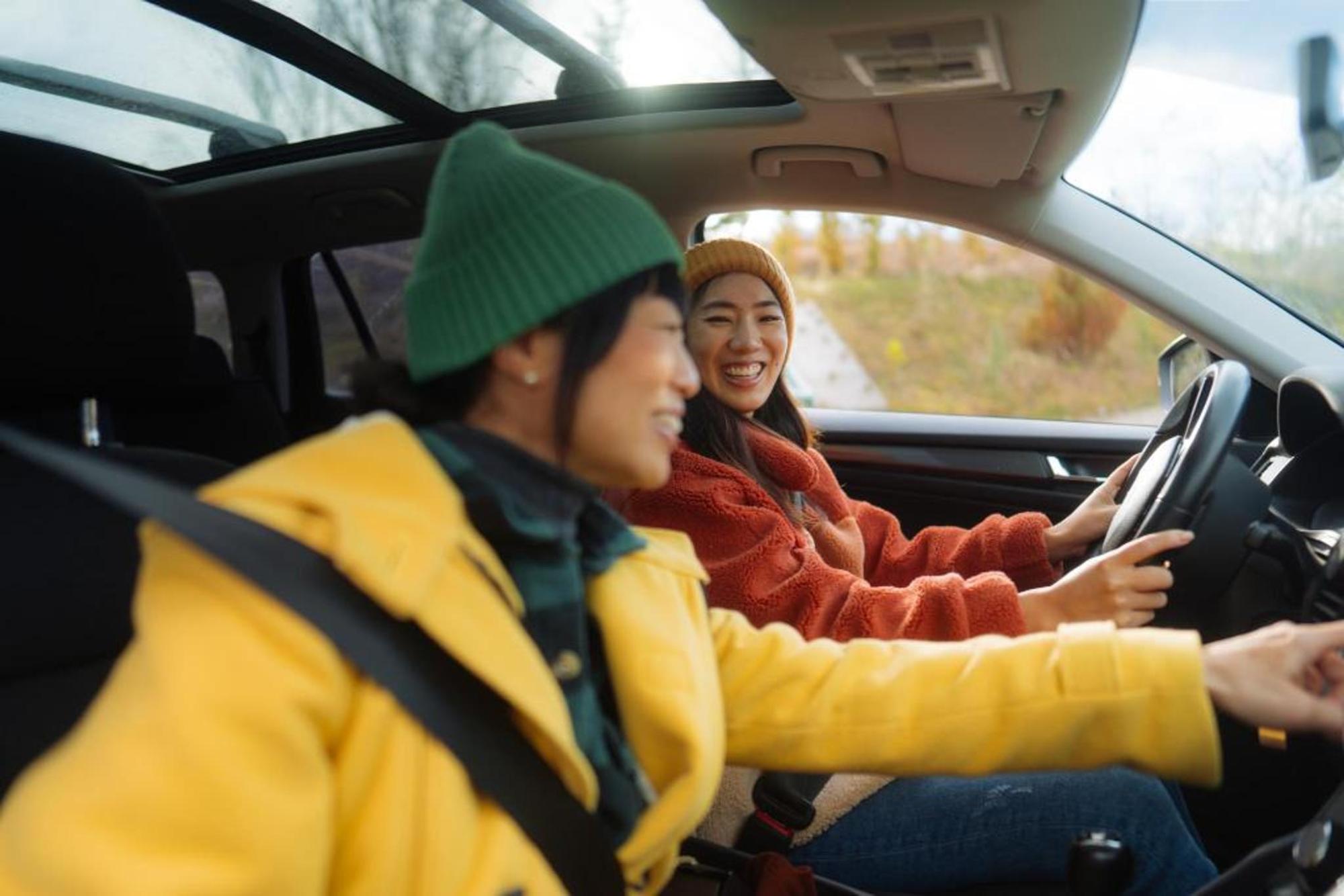 Two people in a car smiling at each other on a road trip