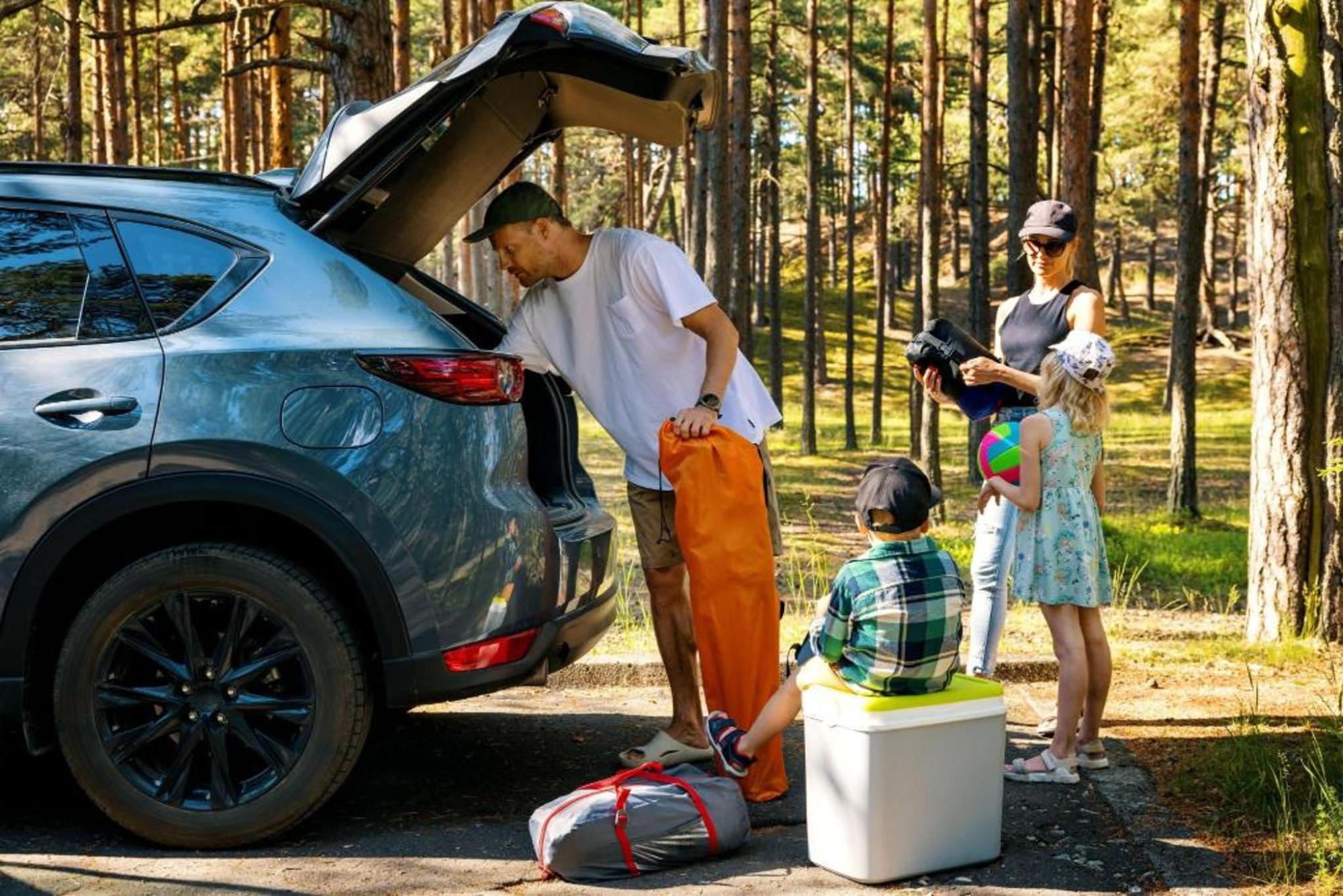 A couple unloads camping gear while their child watches