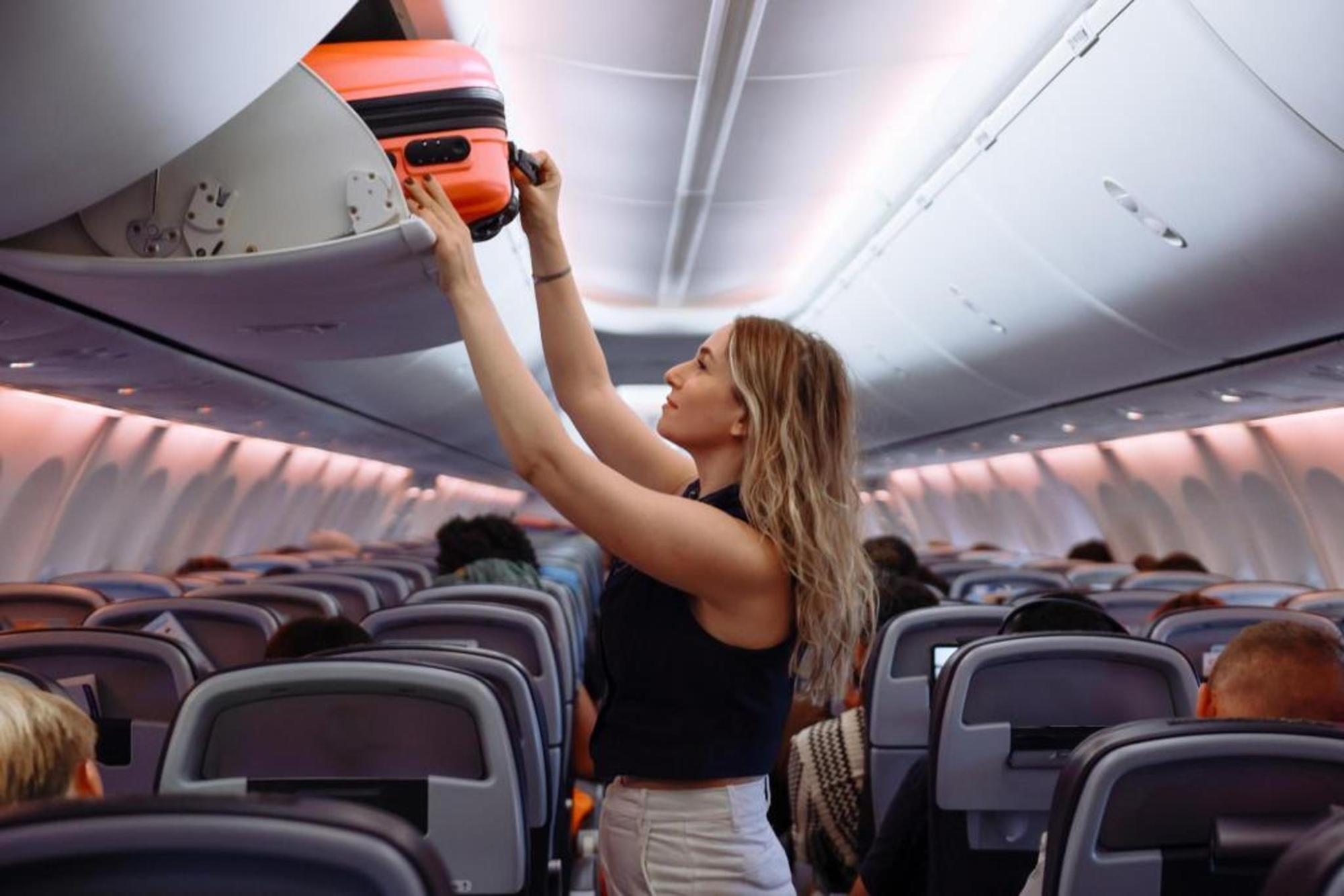 A woman putting her luggage away before her flight 